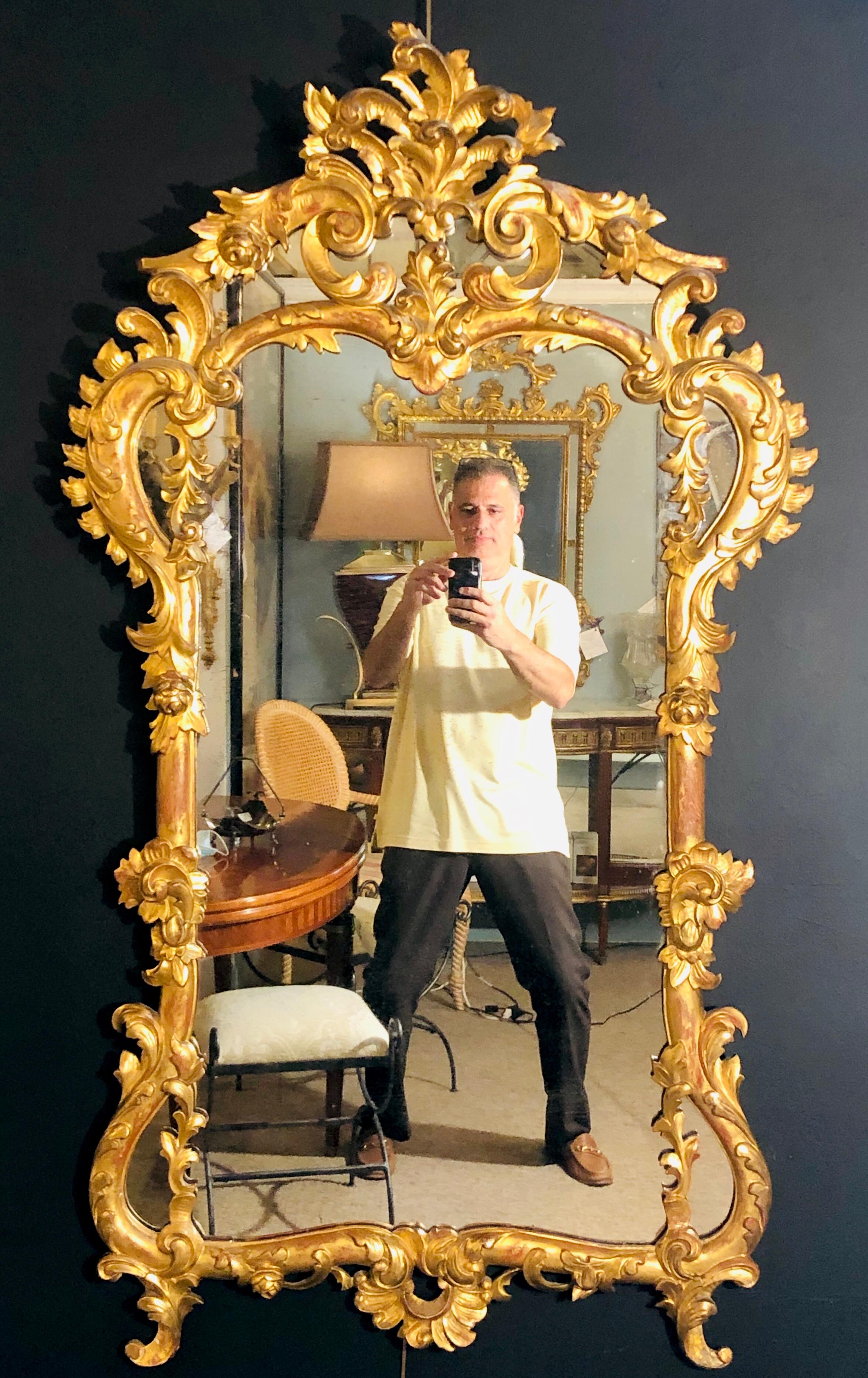 19th century gilt mirror wall or console mirror. A stunning wall or console mirror having a spectacular gilt gold wooden frame with carved roses, leafs and vine showing a clear center mirror set within a pierced carved border. One of the finest
