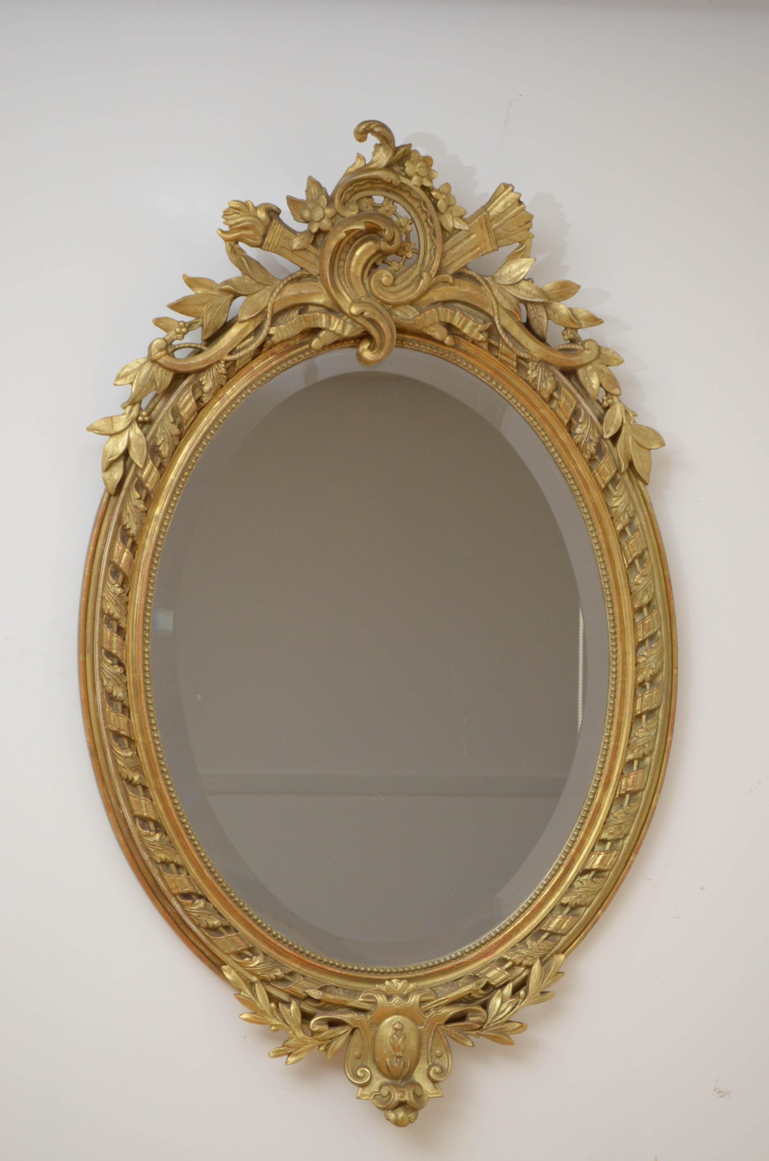Fine 19th century hand carved mirror in Belle Époque style, having original beveled edge glass with some speckle in finely carved frame. The frame is carved with ‘les pearls’ which symbolizes strand of pearls and leaf motifs throughout. The centre