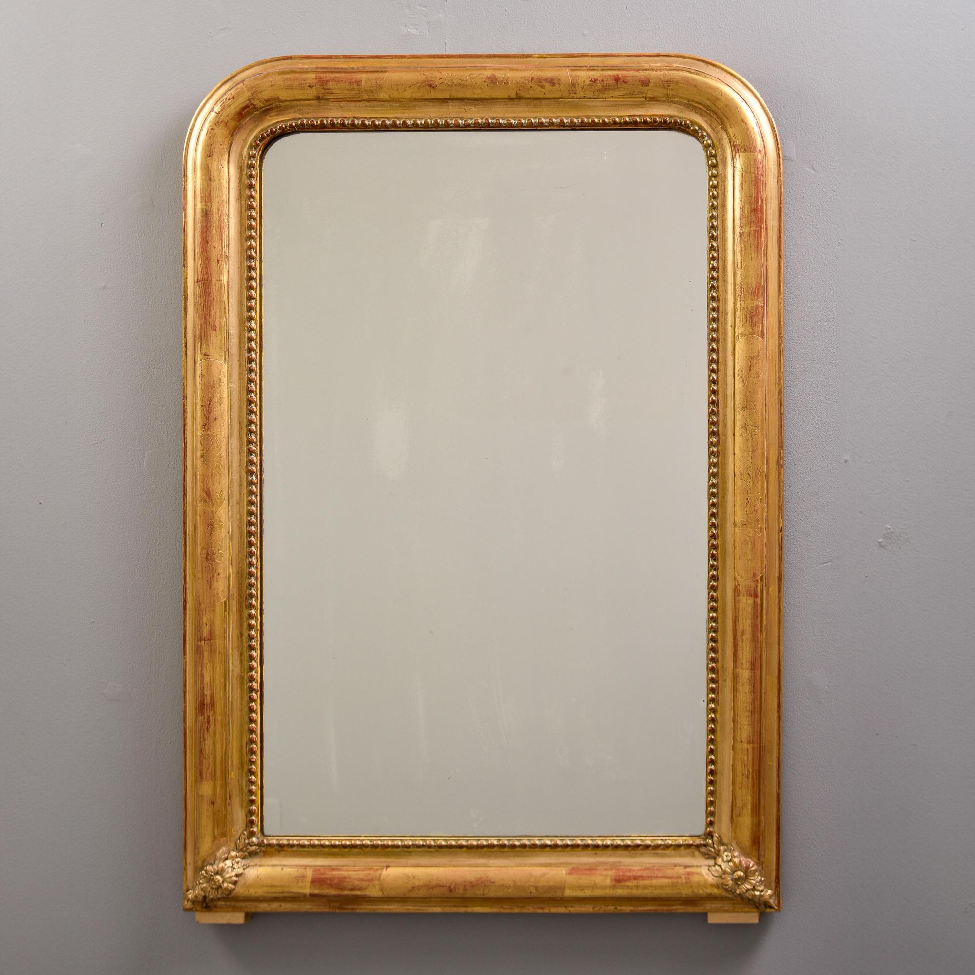 Encontrado en Francia, este marco Louis Philippe de madera dorada data aproximadamente de la década de 1870. Espejo más nuevo. El marco tiene flores esculpidas en las esquinas inferiores y un borde interior de cuentas. El dorado es un dorado cálido