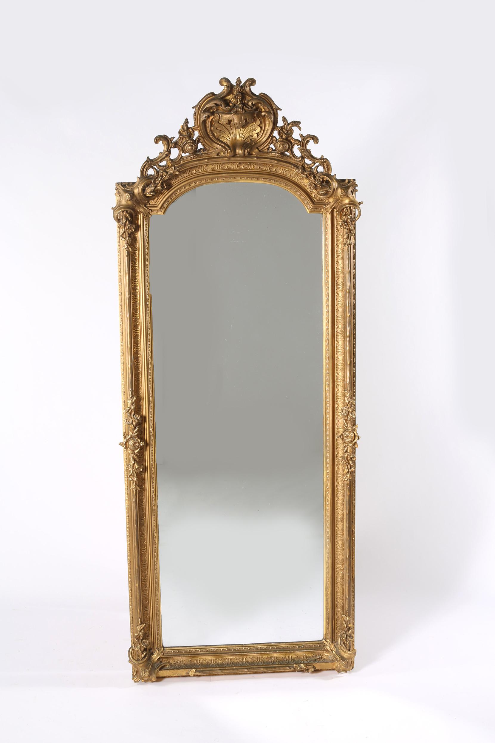 Mid-19th century giltwood framed beveled hanging wall mirror with arch top design details. The mirror is in good antique condition with wear appropriate to age / use. The mirror stand about 77 inches high x 32 inches wide.