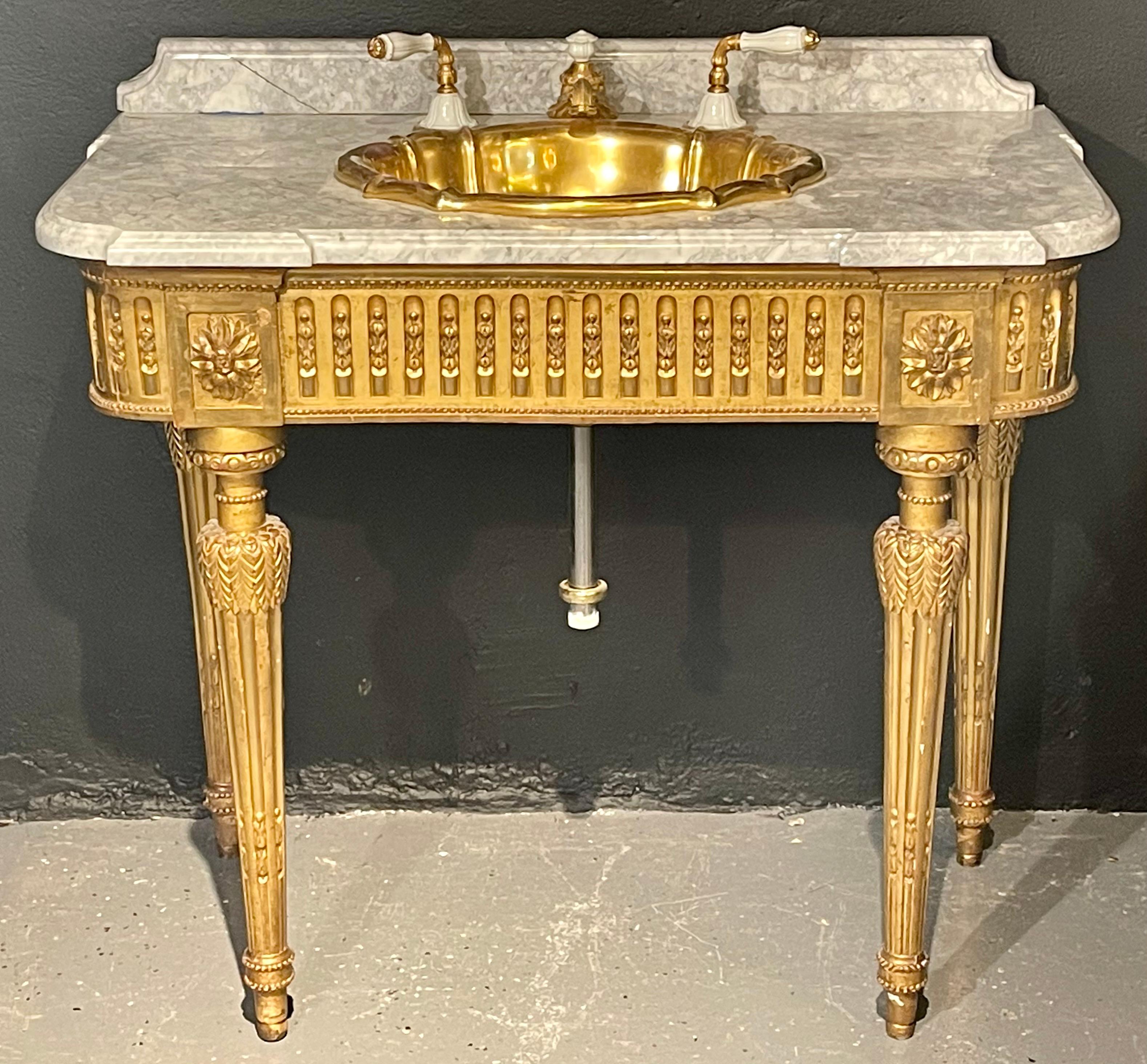 19th century giltwood Louis XVI vanity sink console table. A stunning 19th century console table having a giltwood carved case supporting a think white and gray veined marble top. The finely gilt carved base sitting on four legs leading to a marble