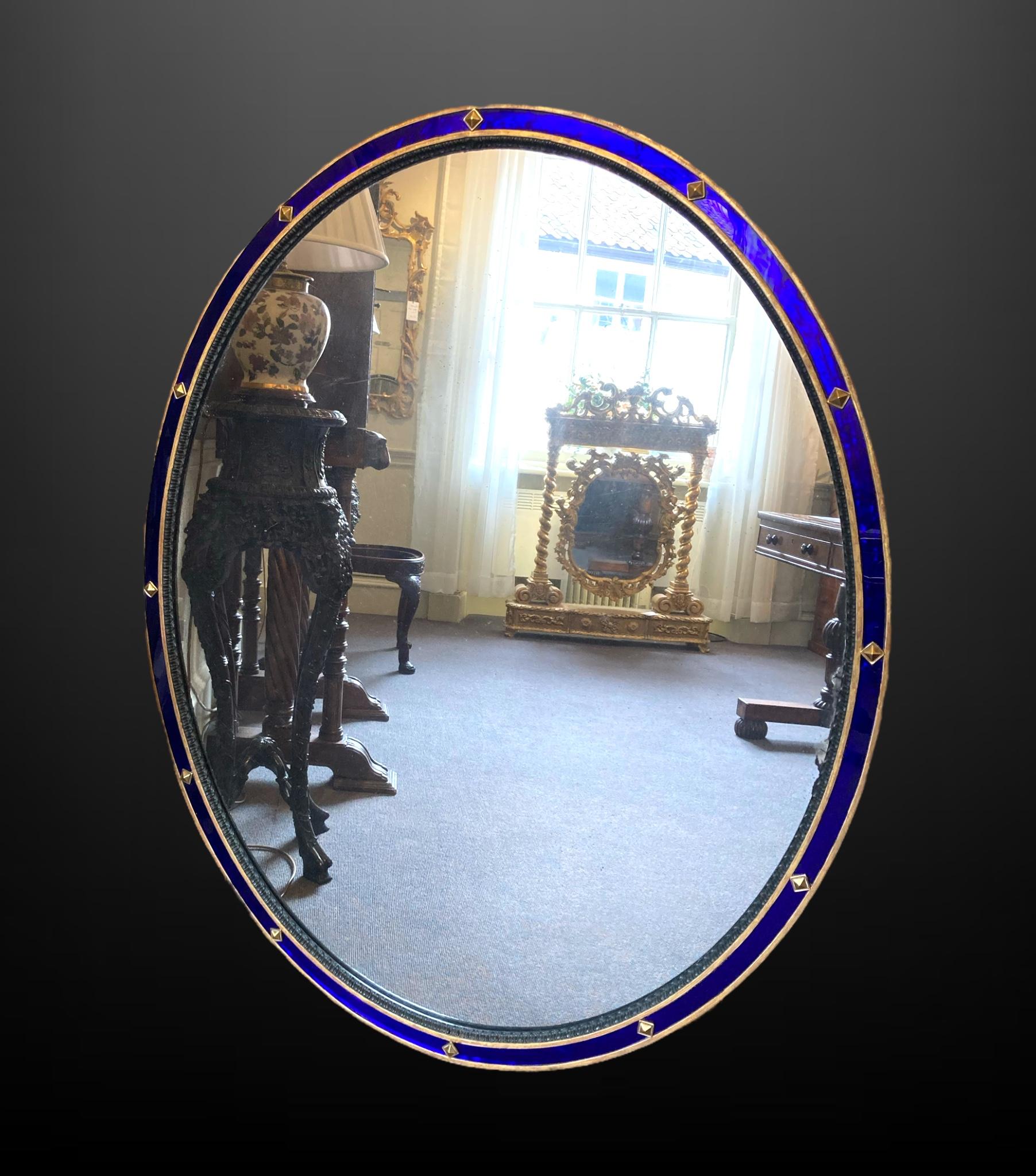 A highly decorative 19th-century giltwood and blue glass oval wall mirror of impressive proportions

The mirror houses a rich blue paneled glass border with mounted decorative studs, ebonised slip, giltwood frame and original mirror plate.

The