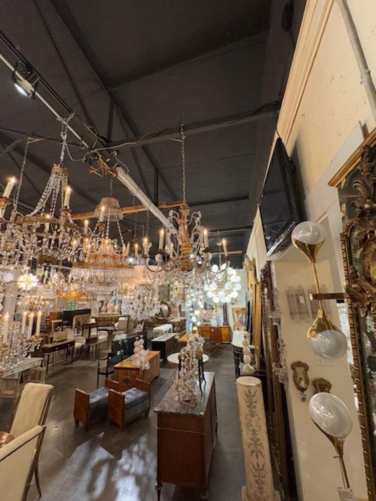 Questo lampadario in legno dorato e cristallo di Genova del XIX secolo presenta una splendida cassa intagliata e splendidi cristalli. Mostra dettagli intricati e la maestria tipica dell'epoca. Questo lampadario è un pezzo senza tempo che emana