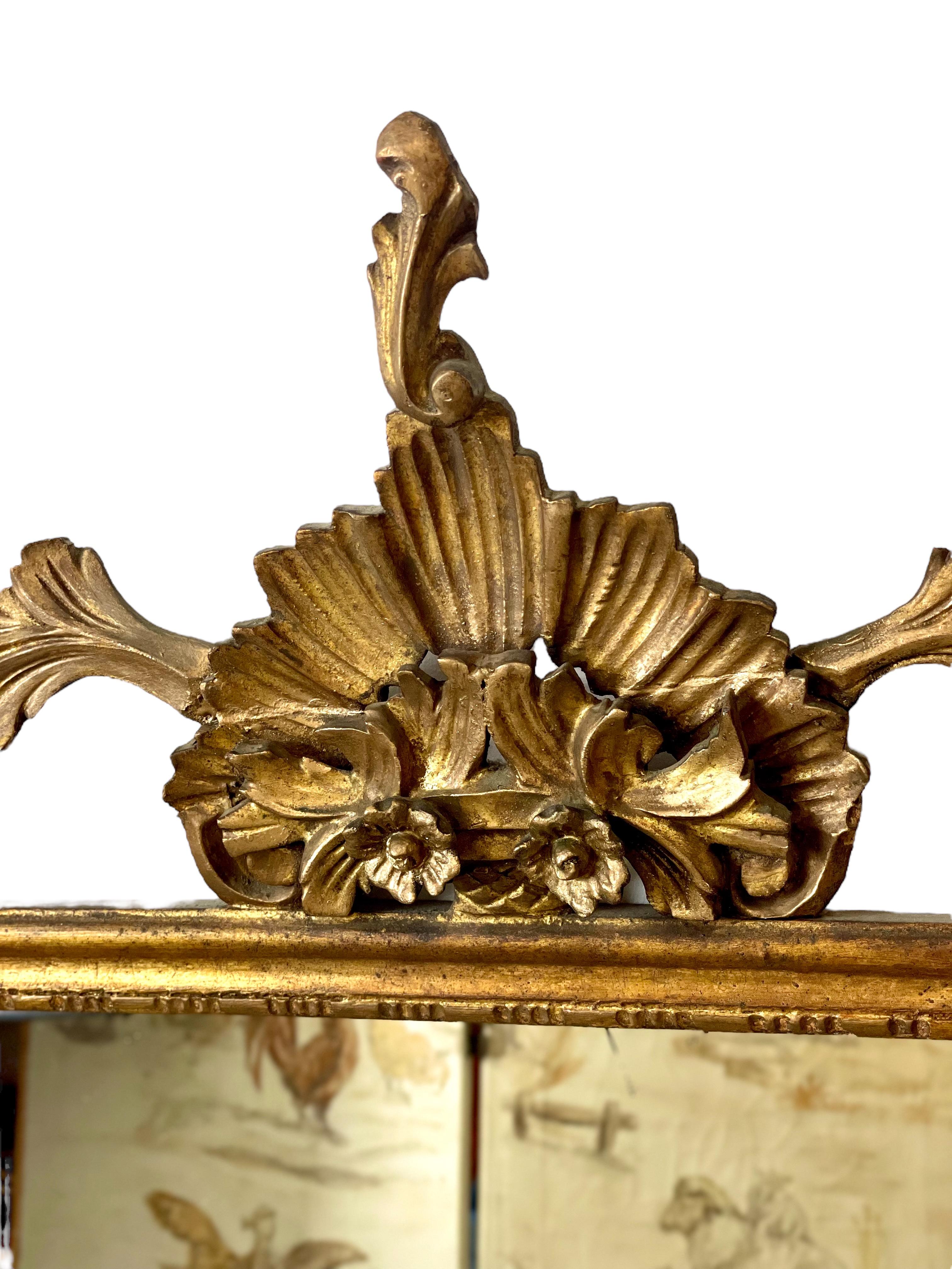 Très beau miroir de cheminée du XIXe siècle en bois doré et stuc. La plaque de miroir rectangulaire est enfermée dans un étroit cadre doré, surmonté d'un cartouche surdimensionné et orné, avec des guirlandes de feuilles d'acanthe et de roses de