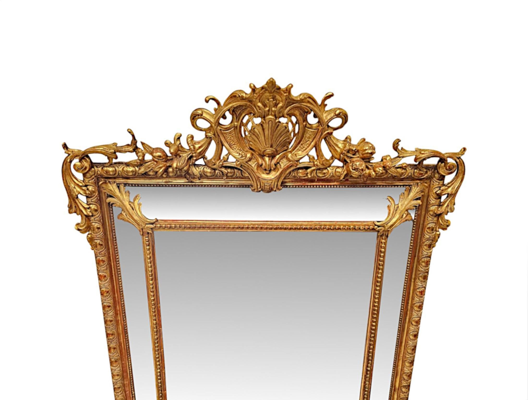 Un favoloso specchio da sala o specchio sovramantello in legno dorato del XIX secolo, finemente intagliato a mano e di qualità eccezionale.  La lastra centrale di vetro a specchio di forma rettangolare è delimitata da un'ulteriore serie di quattro