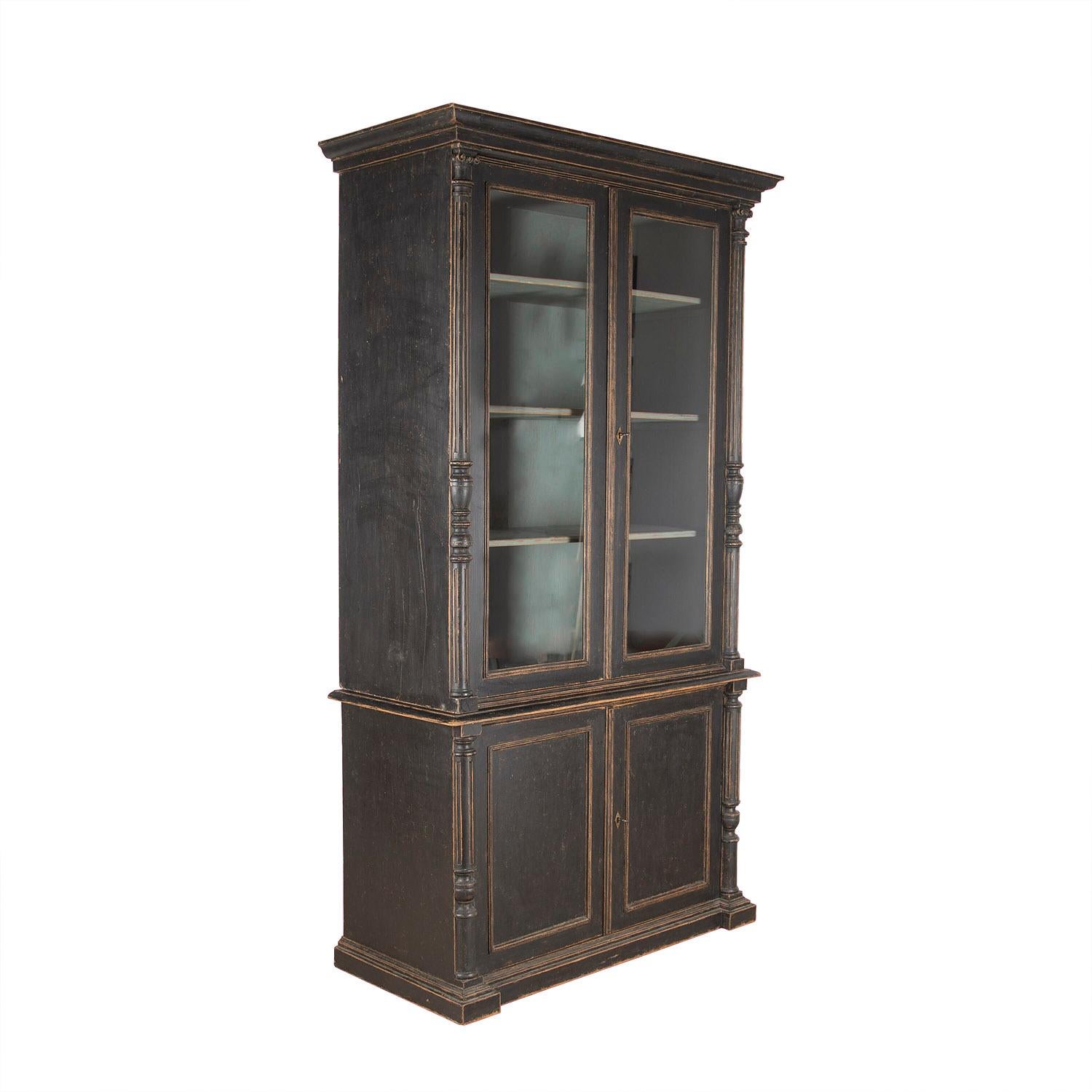 Two part 19th century Swedish bookcase with a carved pediment. Two glazed doors open to storage. A further closed cabinet with two further doors open to storage shelves. This piece features four carved and reeded columns to the exterior edges of the