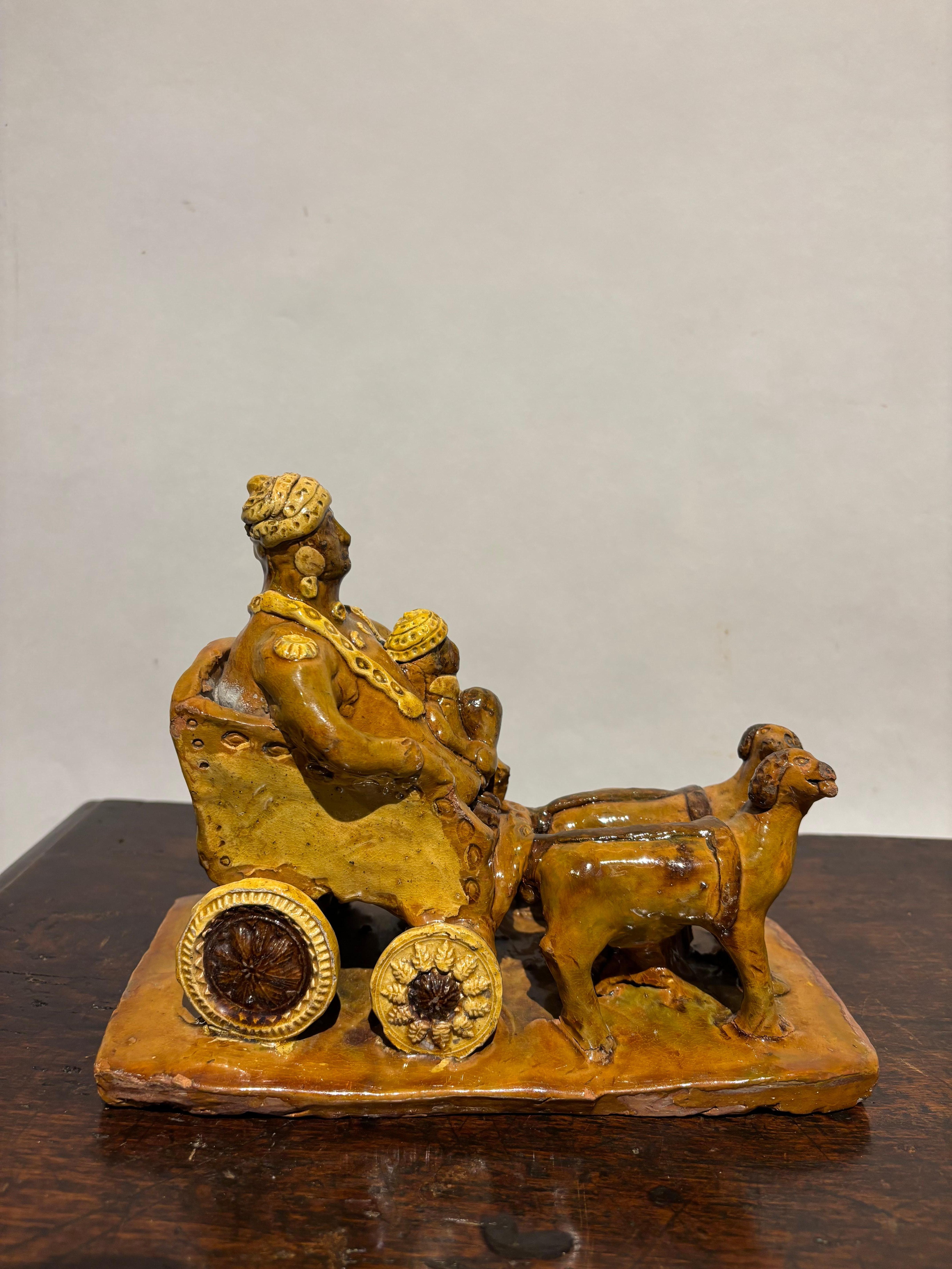 Ceramica smaltata del XIX secolo raffigurante una carrozza che trasporta una figura con turbante che tiene in braccio un bambino, anch'esso con turbante, trainato da due cani. Un pezzo molto insolito e divertente che, onestamente, è un po' un
