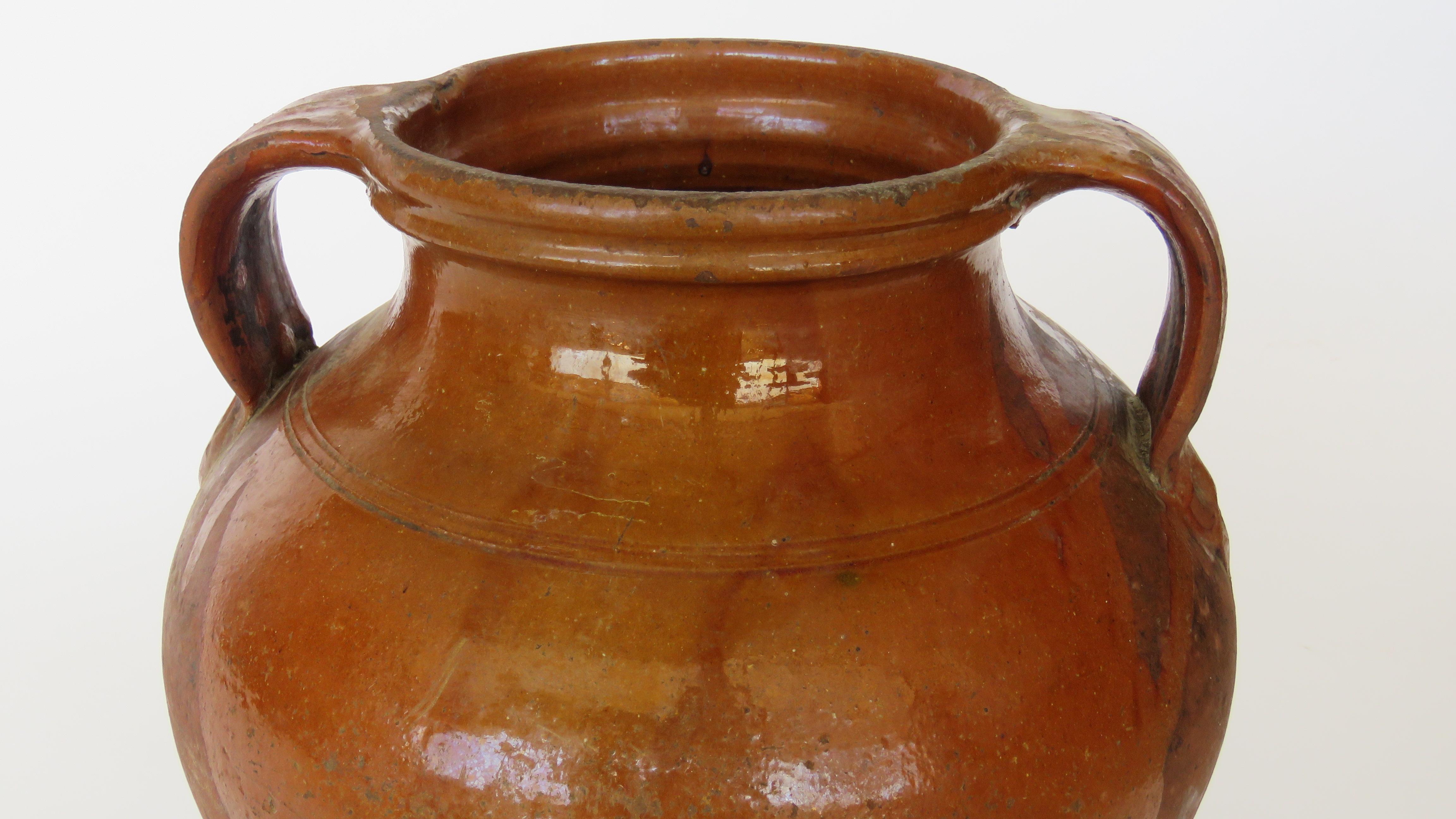 Hand coiled part mahogany brown glazed pot with two handles.