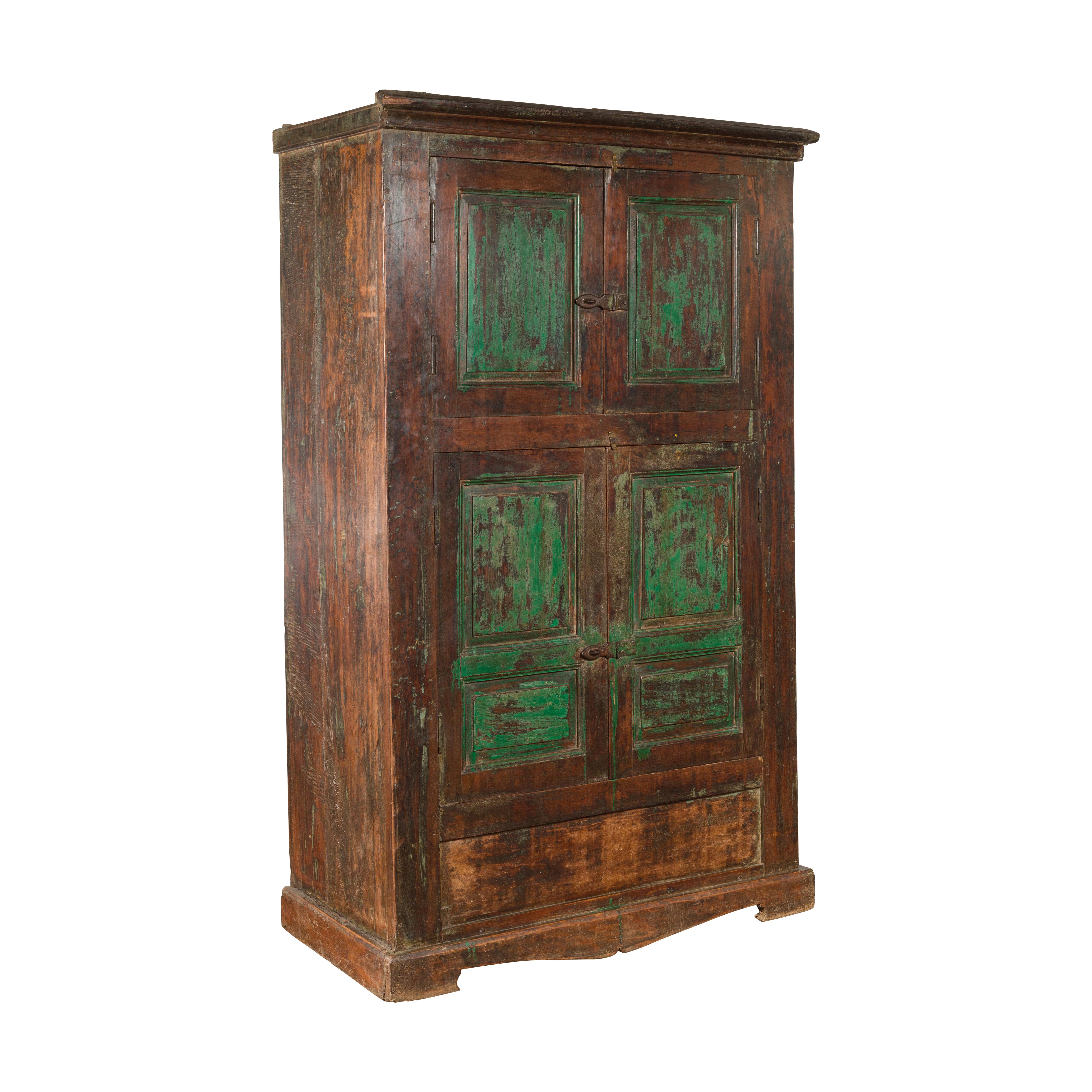 An Indian hand-carved painted wood cabinet from Goa, with green accents and distressed patina. Created in Goa, a Portuguese colony for 450 years until it was annexed by India in 1961, this 19th century cabinet features a simple cornice sitting above