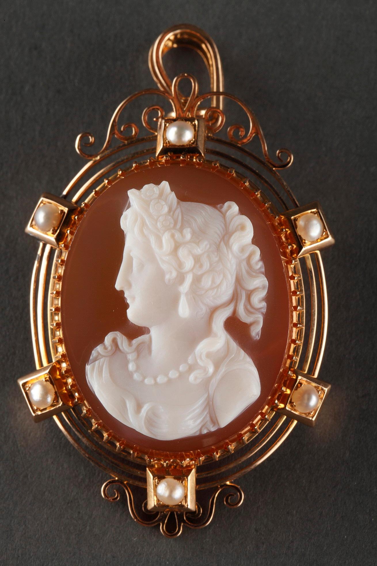 Cameo on orange-pinkagate featuring a young woman looking toward the left. The artist intricately sculpted the white vein of the agate to bring the delicate profile to life. This young woman in bust has hair up and girded with a floral diadem. She