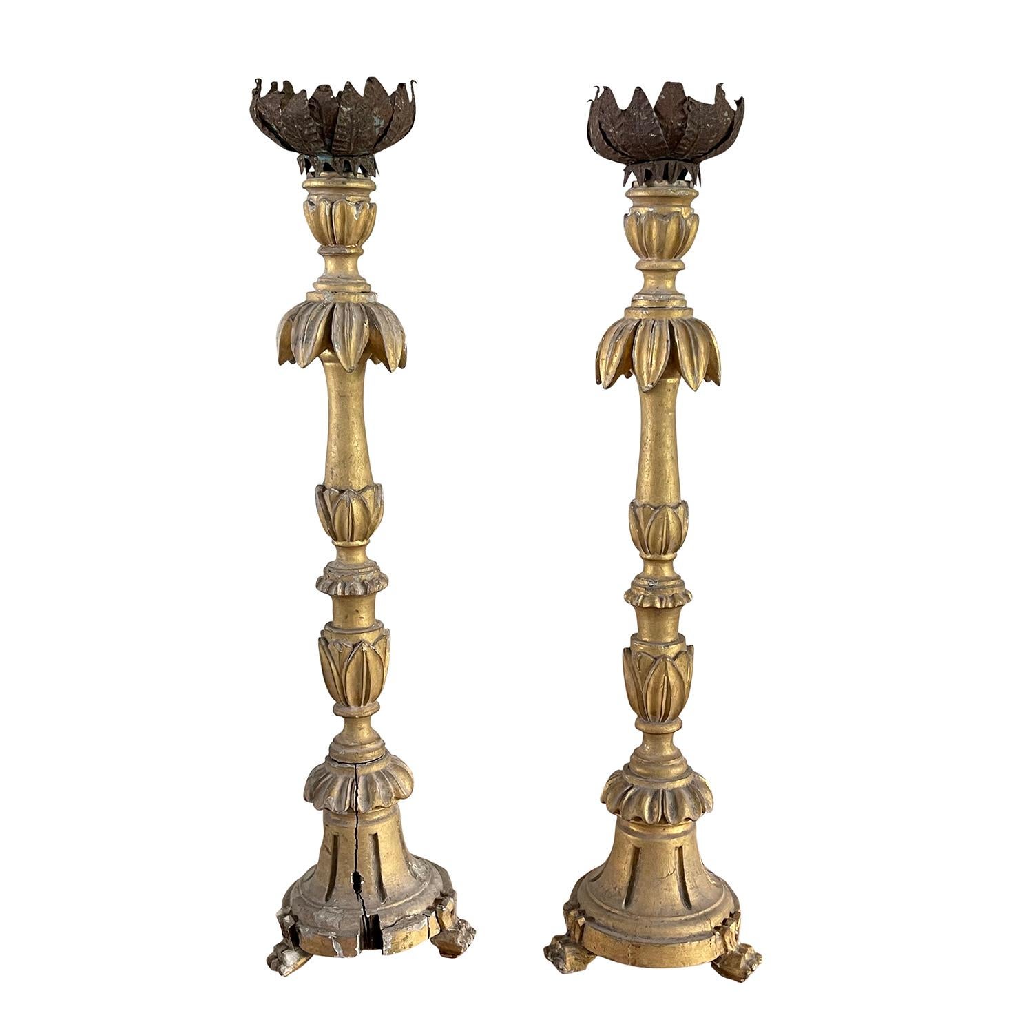 An antique pair of mid 19th century French candle holders with delicate Pinewood carvings set on a tripod base, in good condition. The structure has the original polychrome finish in silver and gold. The candle holders are topped with a metal plate