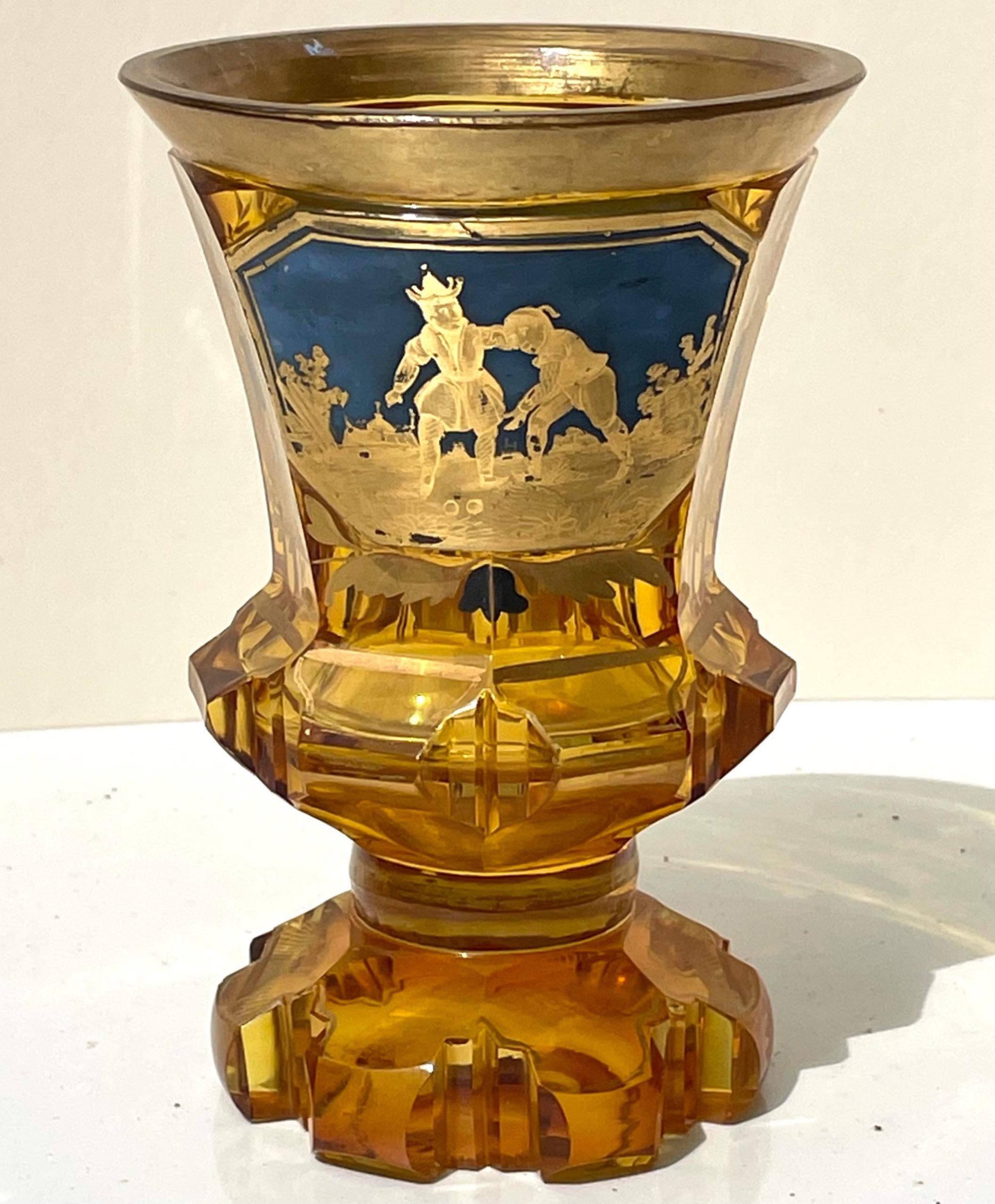 19th century gold gilded bohemian amber glass enamel cut goblet. 

Glowing amber vessel with gilded rims and incised designs on foot and terraced stem. Highly stylized piece in with a blue enamel painted and cut gold gilded cartouche in