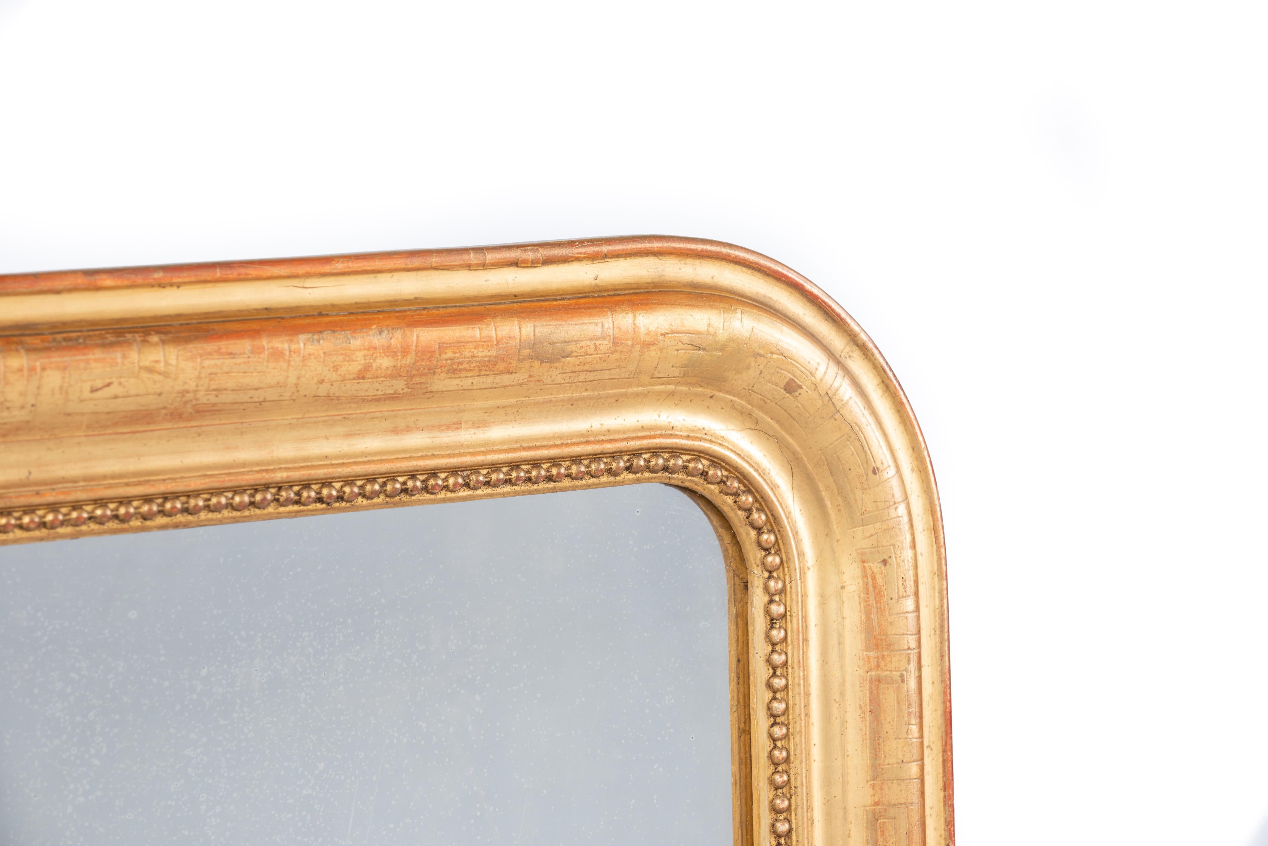 On offer here is a beautiful gold leaf gilt French mirror that was made in the late 19th century, circa 1880. It has the upper rounded corners typical for the Louis Philippe style. The mirror frame has an elegant pearl beading surrounding the glass.