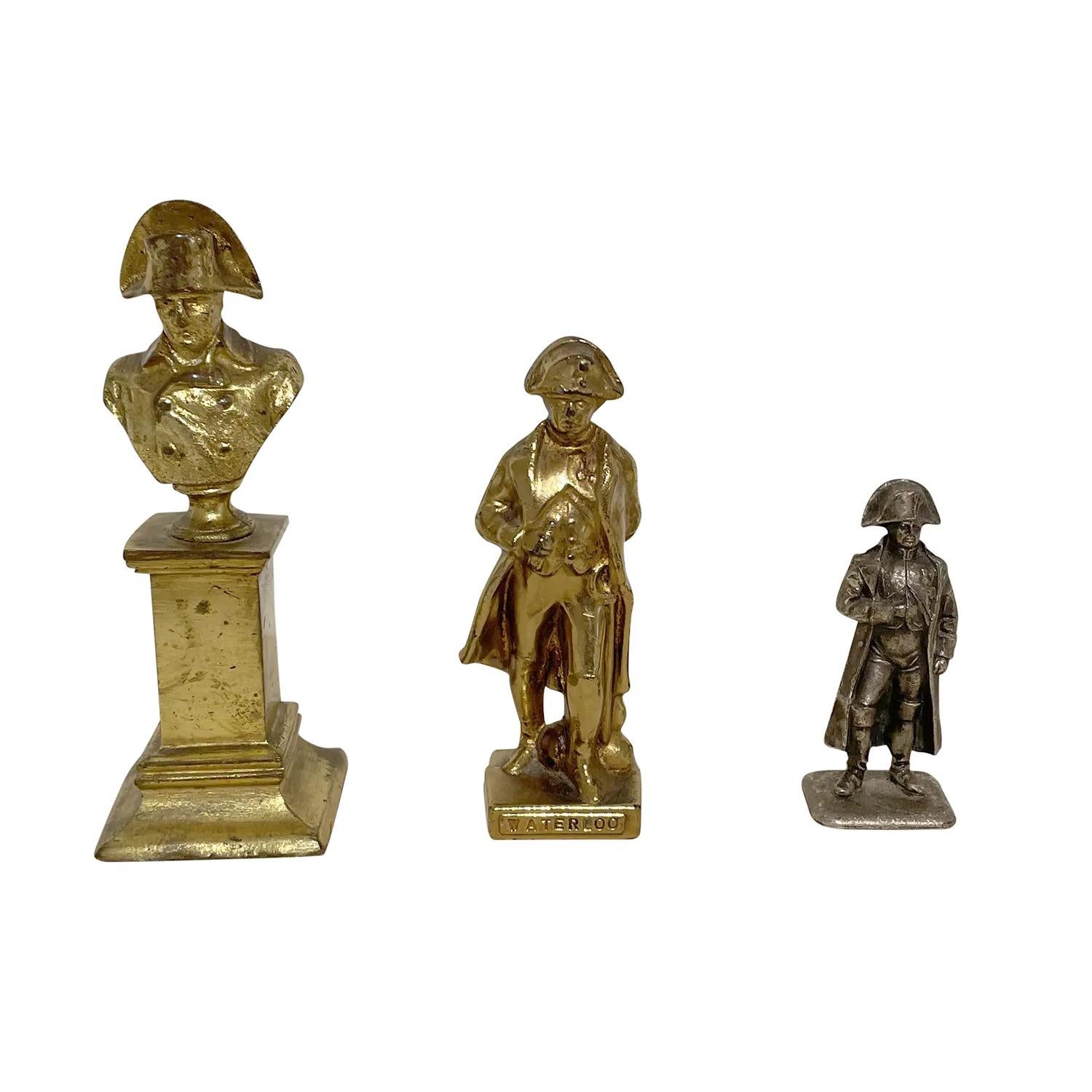 A gold-silver, antique French set of three Napoleon Bonaparte sculptures made of hand crafted metal and gilded bronze, in good condition. The particularized décor pieces represent the First French Empire time period, era also known as Napoleonic