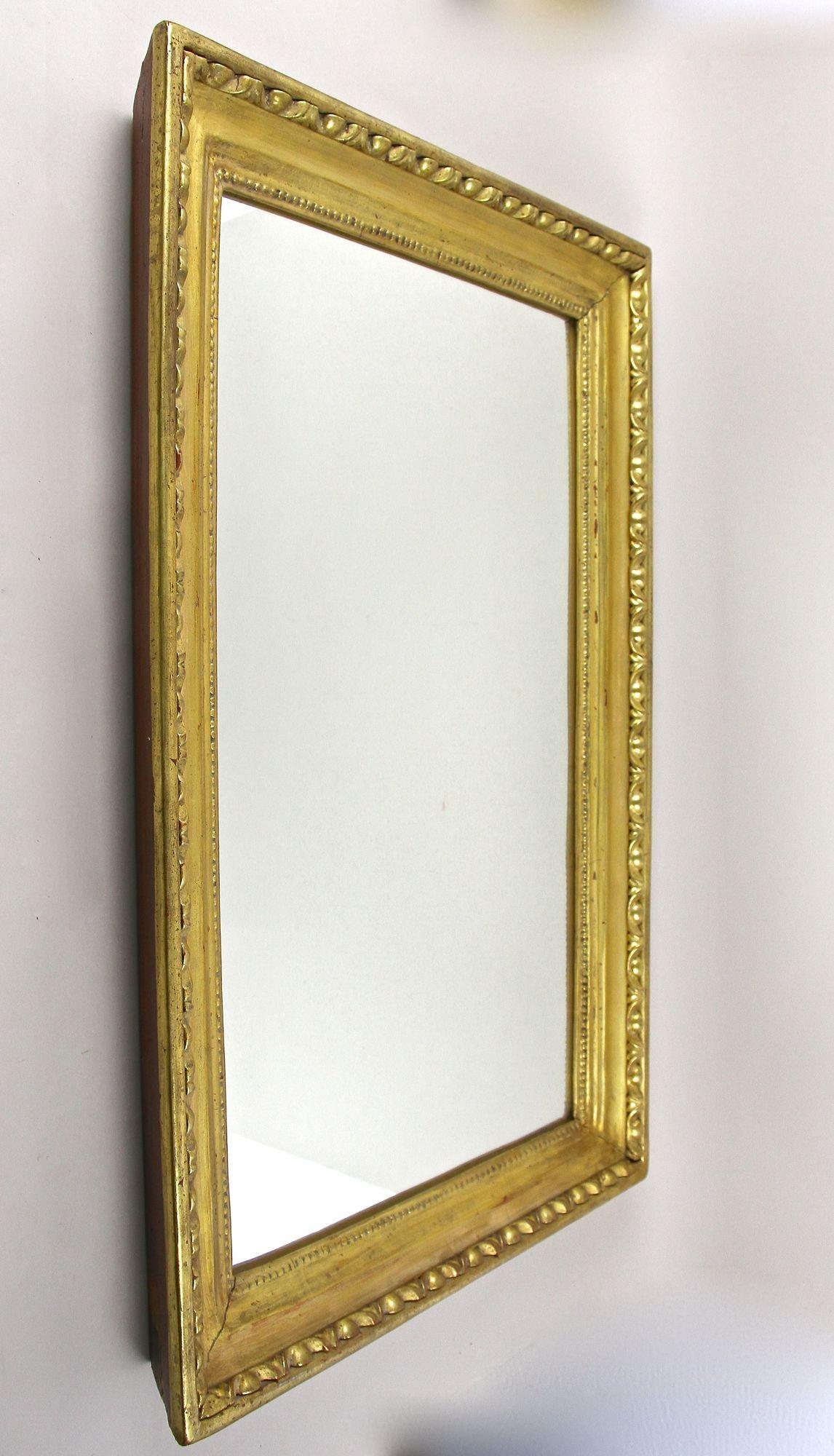 Séduisant miroir mural autrichien doré de la célèbre période Biedermeier, vers 1830. Le cadre large et profondément rainuré (en partie sculpté, en partie stuqué) a été recouvert d'un 
