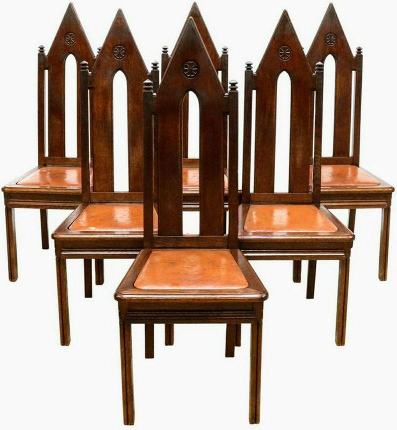 A magnificent set of six Victorian era Gothic oak dining chairs from the 19th century. Hand-crafted in France, having a high steeple shaped back with open arched splat, carved floral medallion, topped by squared pyramid finials, with an inset padded