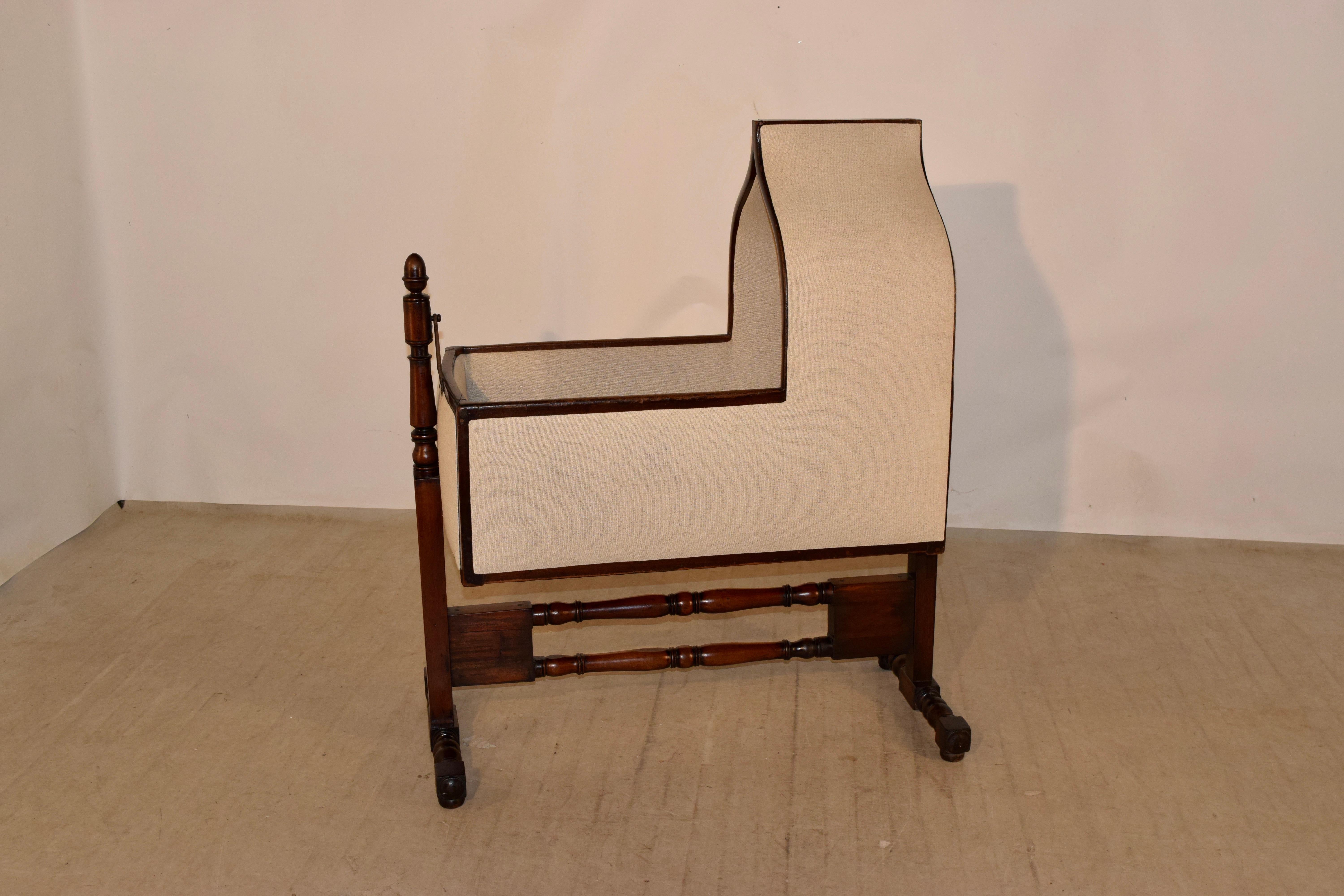 19th century Gothic Revival English cradle with hand-turned posts and stretchers. In that time period, it would be customary for a cord to be attached to one of the finials order to allow someone to pull the cord and rock the cradle from a distance.