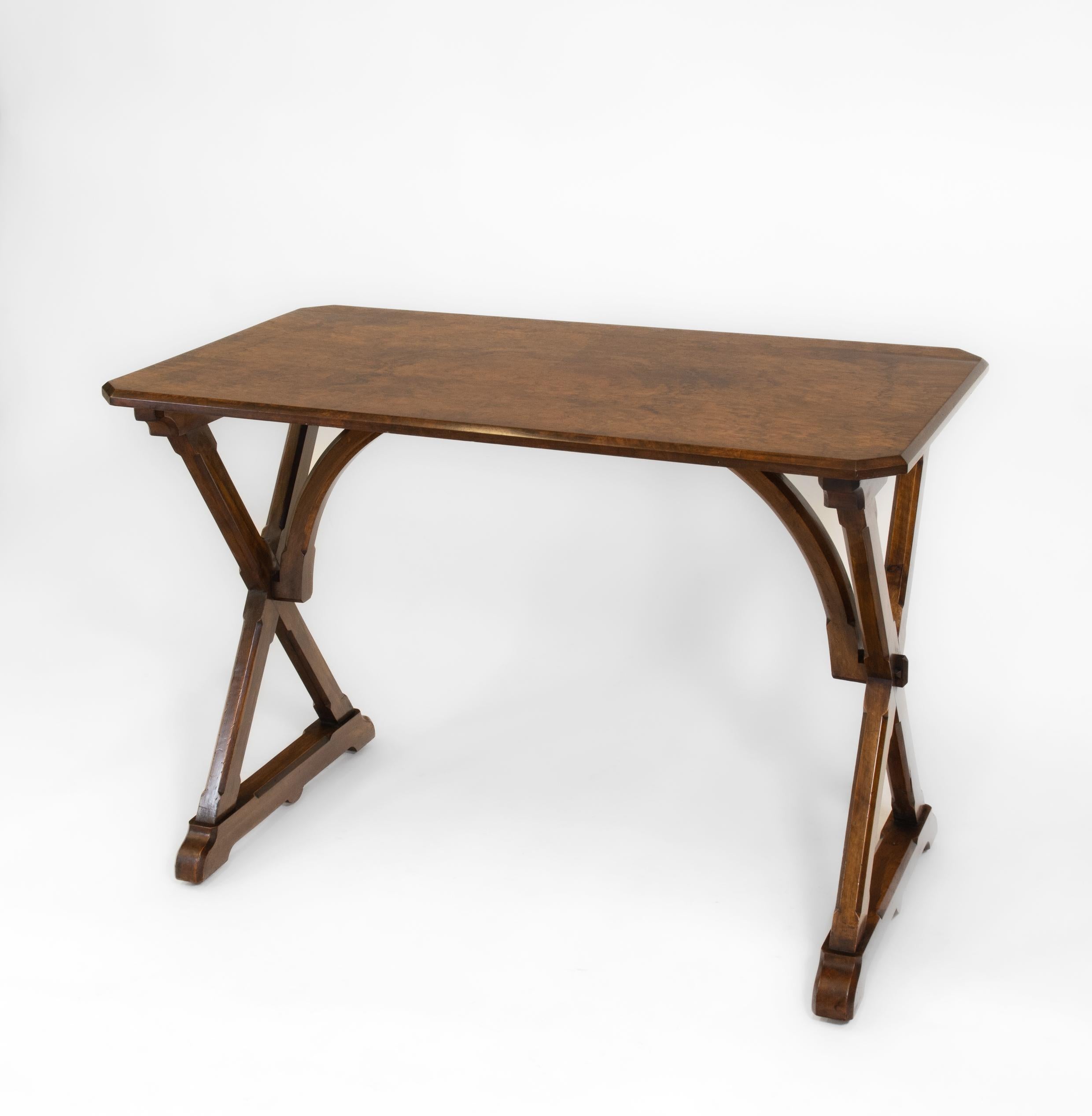 A 19th Century burr walnut and walnut Gothic Revival writing side table in the A W Pugin manner. English. Circa 1860.

The table having a burr walnut top with canted corners, supported on a walnut cross-frame with chamfered edging and visible pegs