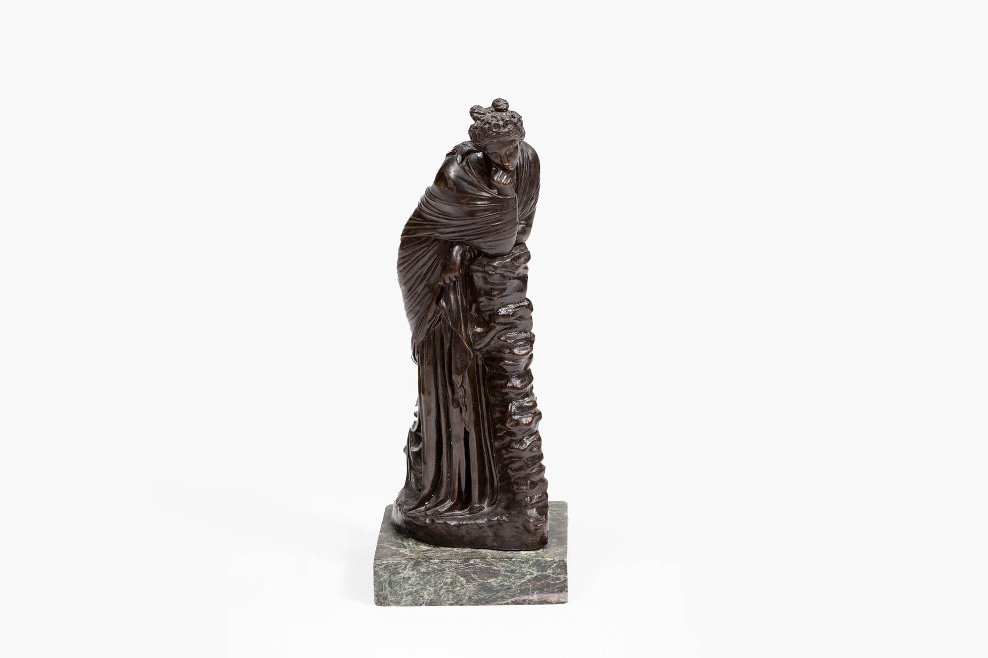 19th Century Grand Tour bronze figurine of Polyhymnia daughter of Zeus, after the antique, standing at full-length, resting against a pile of stacked stones. She wears a long dress, and her hair tied up in a wreath of flowers. The statue sits on a