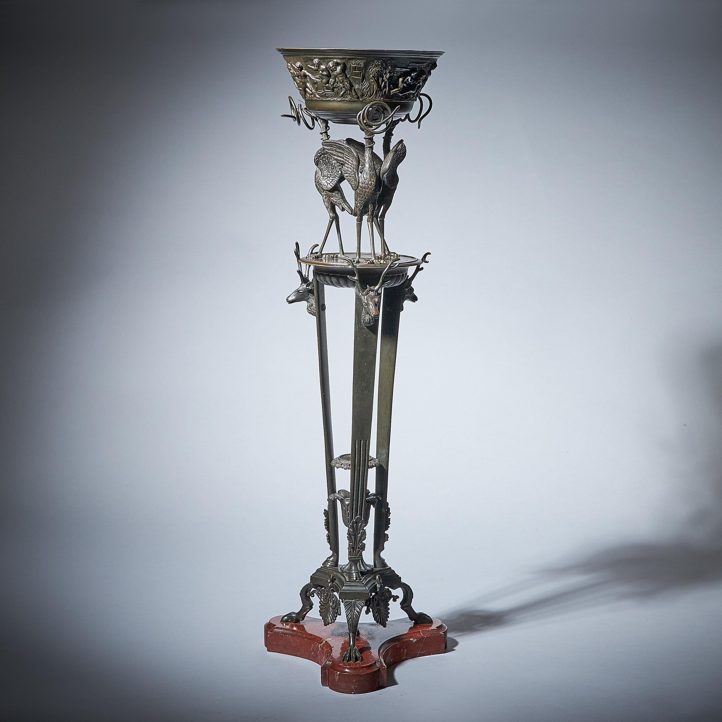 A superb grand tour 19th-century grand tour bronze tiered tripod-stand supporting a highly decorated jardiniere raised by three cranes. 

Each of the three tripod legs is fitted with a stag to the top, stop-reeded and hoofed to the base with a