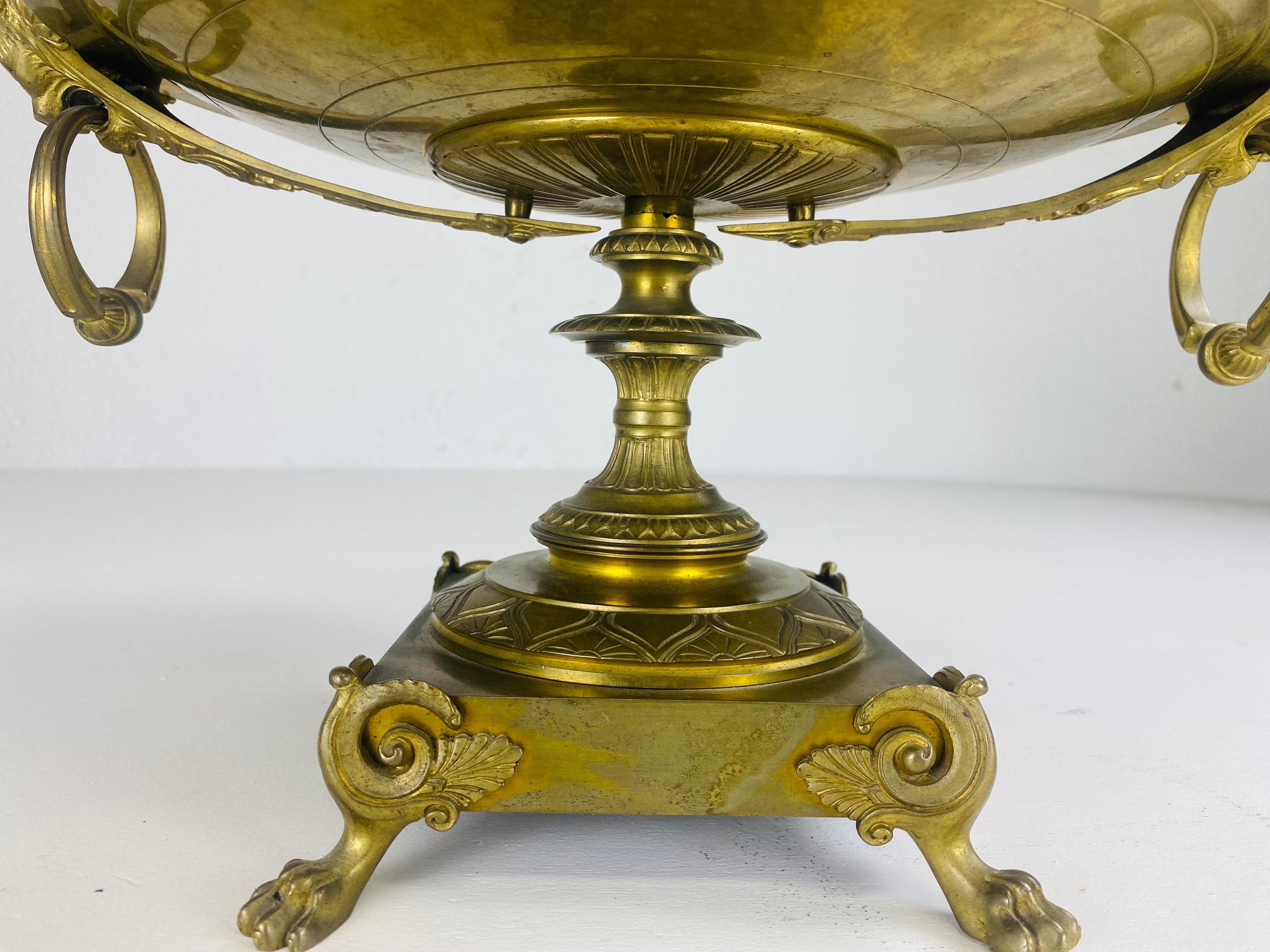 This is a late 19th century Italian neo classical bronze compote. This classical bronze compote has ornate claw feet and mythical figures on either side of the bowl with rings. This classical compote has a Romanesca medallion in the center in