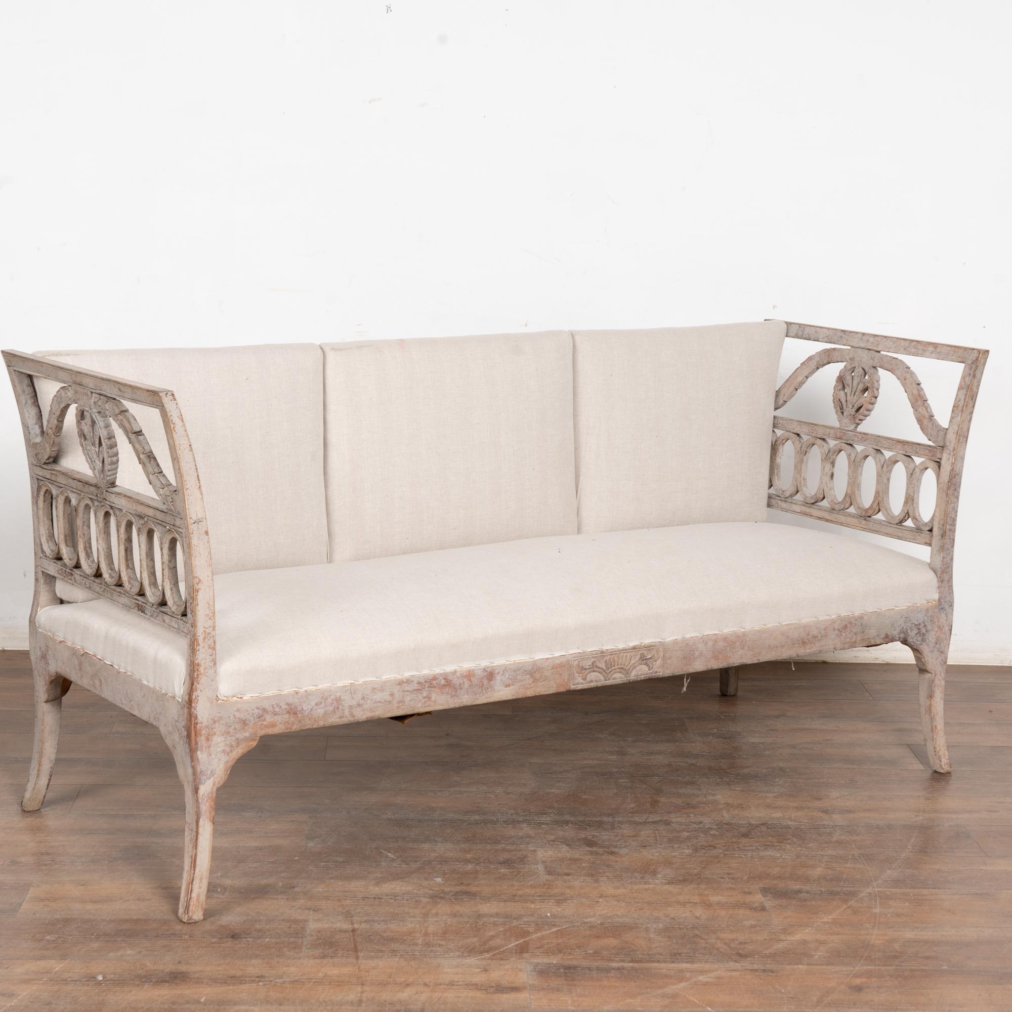 This elegant Swedish Gustavian sofa or settee has graceful decorative arms curving outward. 
Please enlarge and examine the close up photos to appreciate the newer, professionally applied antique soft gray painted finish, distressed and rubbed to