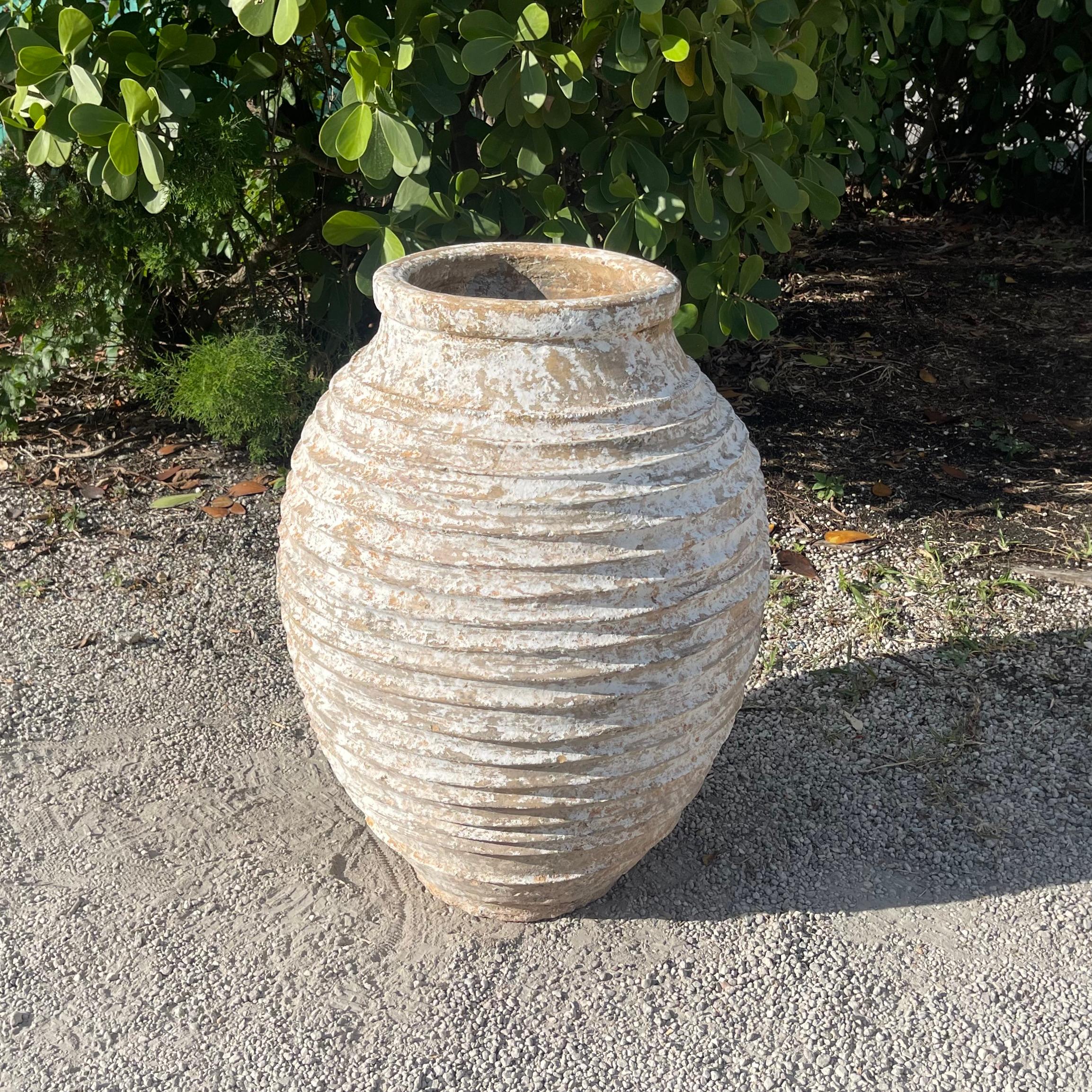 Un'anfora greca per olio d'oliva del Peloponneso con la tipica decorazione artigianale a coste Nekuma sul corpetto rotondo. La patina bianca veniva applicata per proteggere la terracotta dalle condizioni climatiche avverse o per raffreddare il cibo