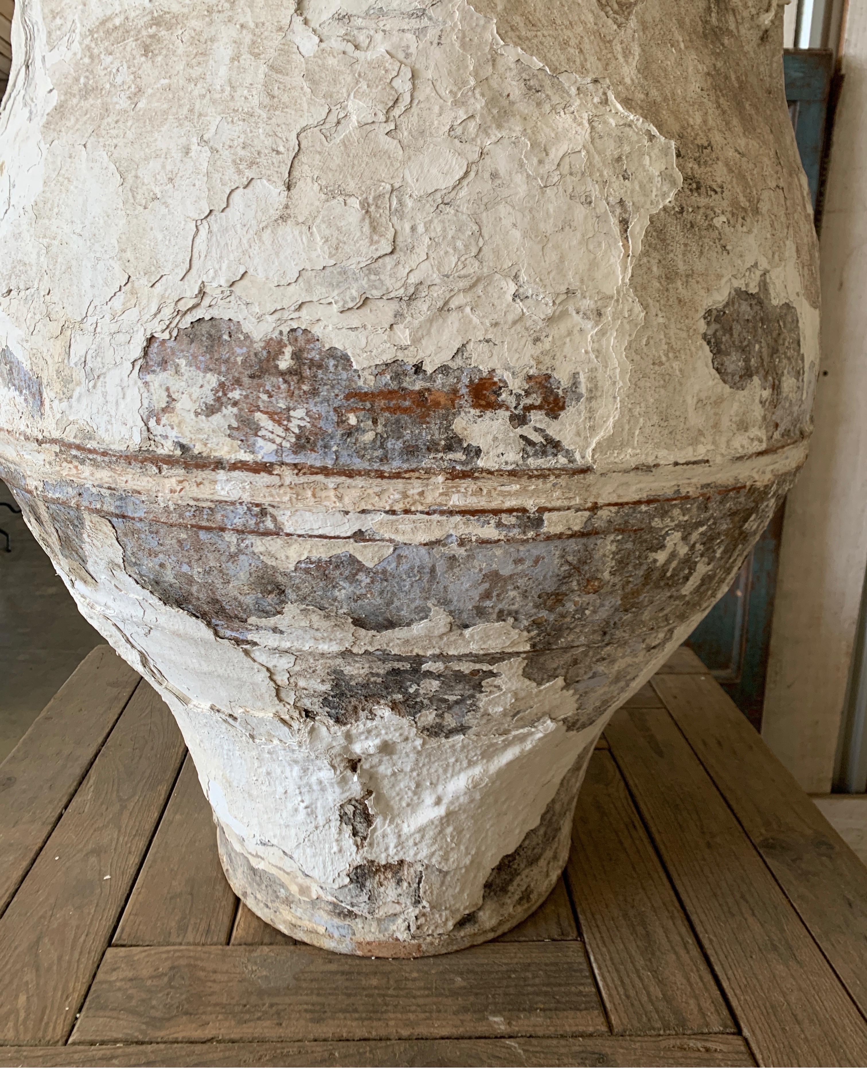 This beautiful olive jar is large in scale and originates from Greece. It has a wonderful plastered white finish with a few hints of blue. Mouth opening is 20 inches width, bottom bases is 15 diameter. Measures: 40.38 tall x 31 wide x 31 deep.