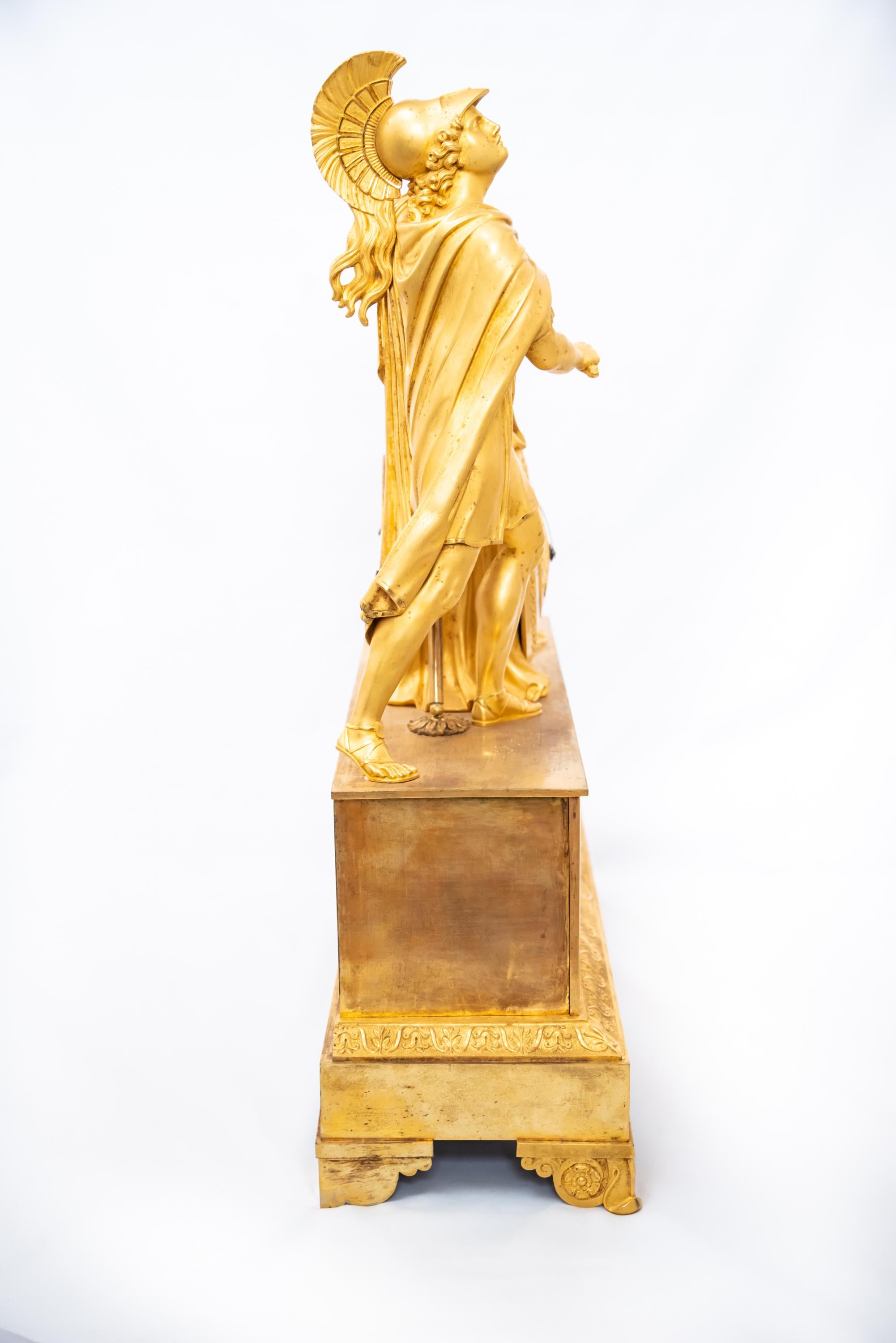 Pendule française en bronze doré au feu représentant un guerrier grec, époque Restauration, 1815-30. Le mécanisme à fil de soie est en bon état de fonctionnement avec la clé et le pendule.