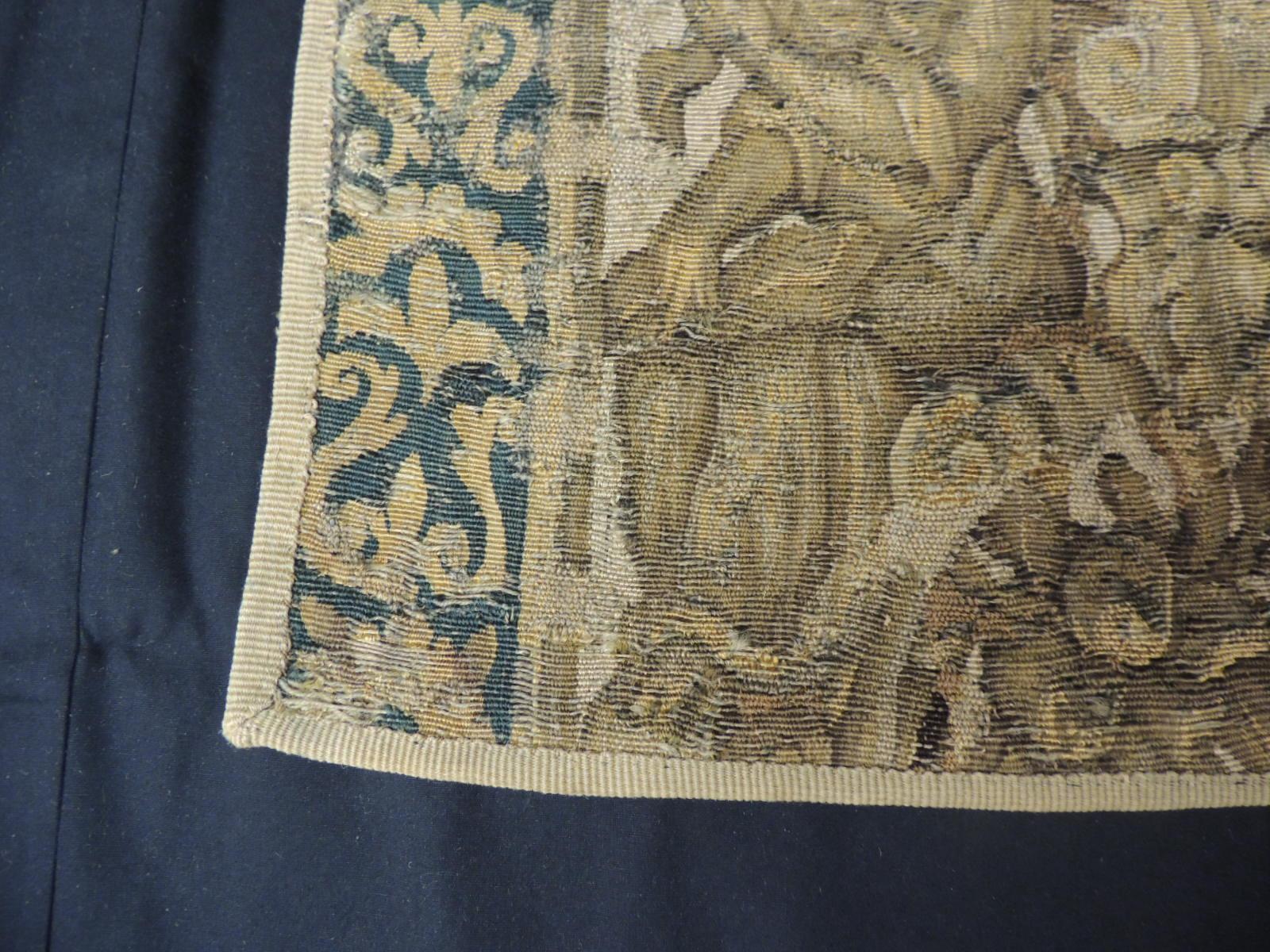 19th century green and gold verdure tapestry fragment, depicting an angel face, two harp playing ladies, a lion face, birds, fruits and an urn.
Framed with small french ribbon all around and backed with linen.
