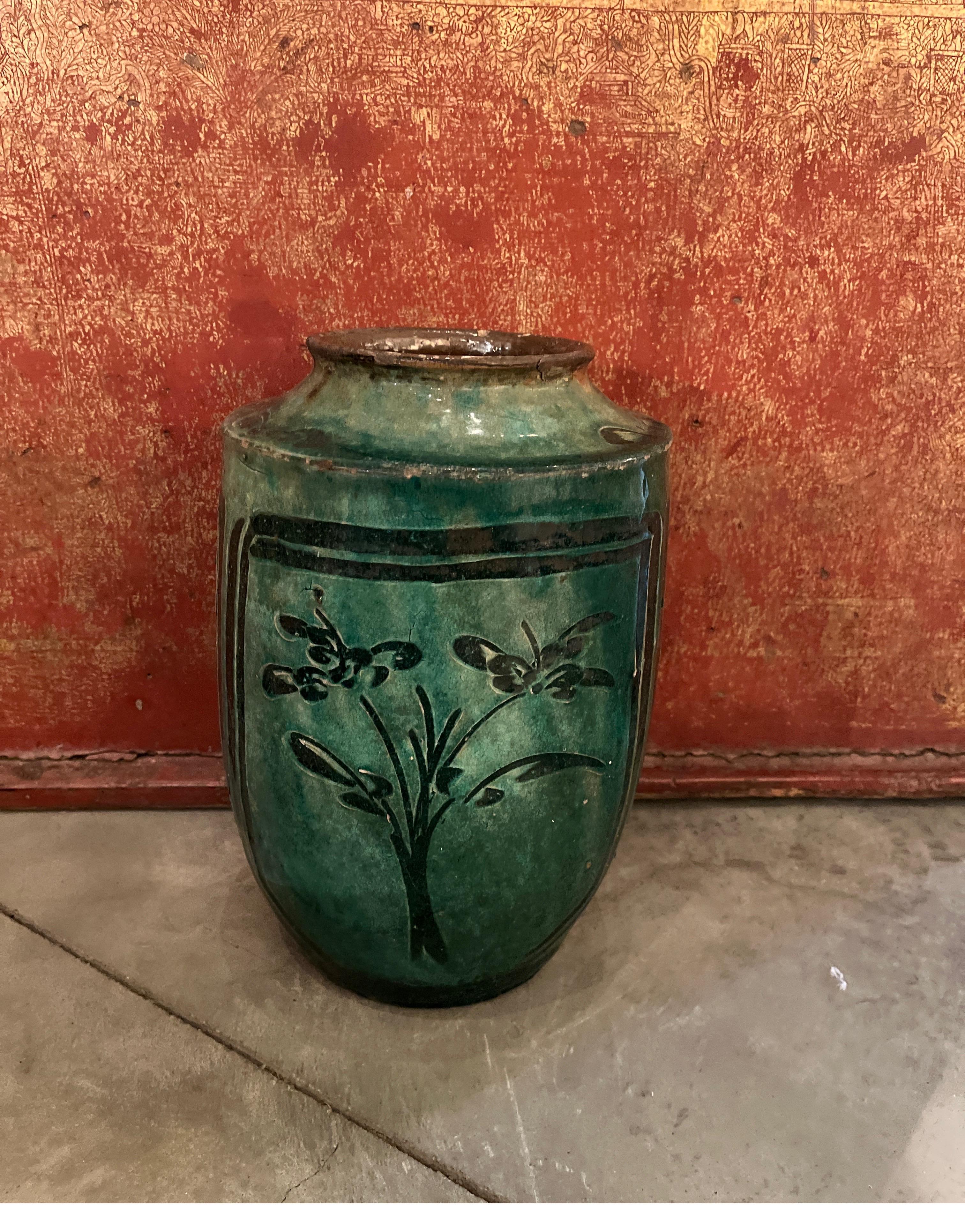 A stunning green glazed antique ceramic Chinese food jar with three fanciful and expertly hand painted floral images all around the vessel. This piece fairly glows with history and it's vibrant color. Remarkable glazes like this one are really not