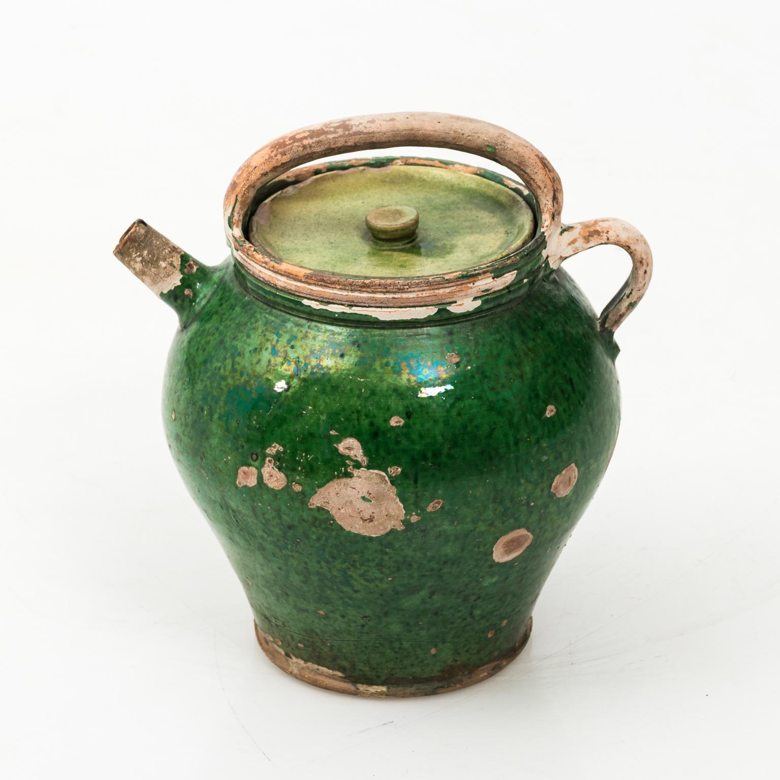 French confit jug with lid in a green glaze, circa 1880. Please note of wear consistent with age including worn surface loss to the paint along with chips to the spout. The lid itself also has color loss due to age.