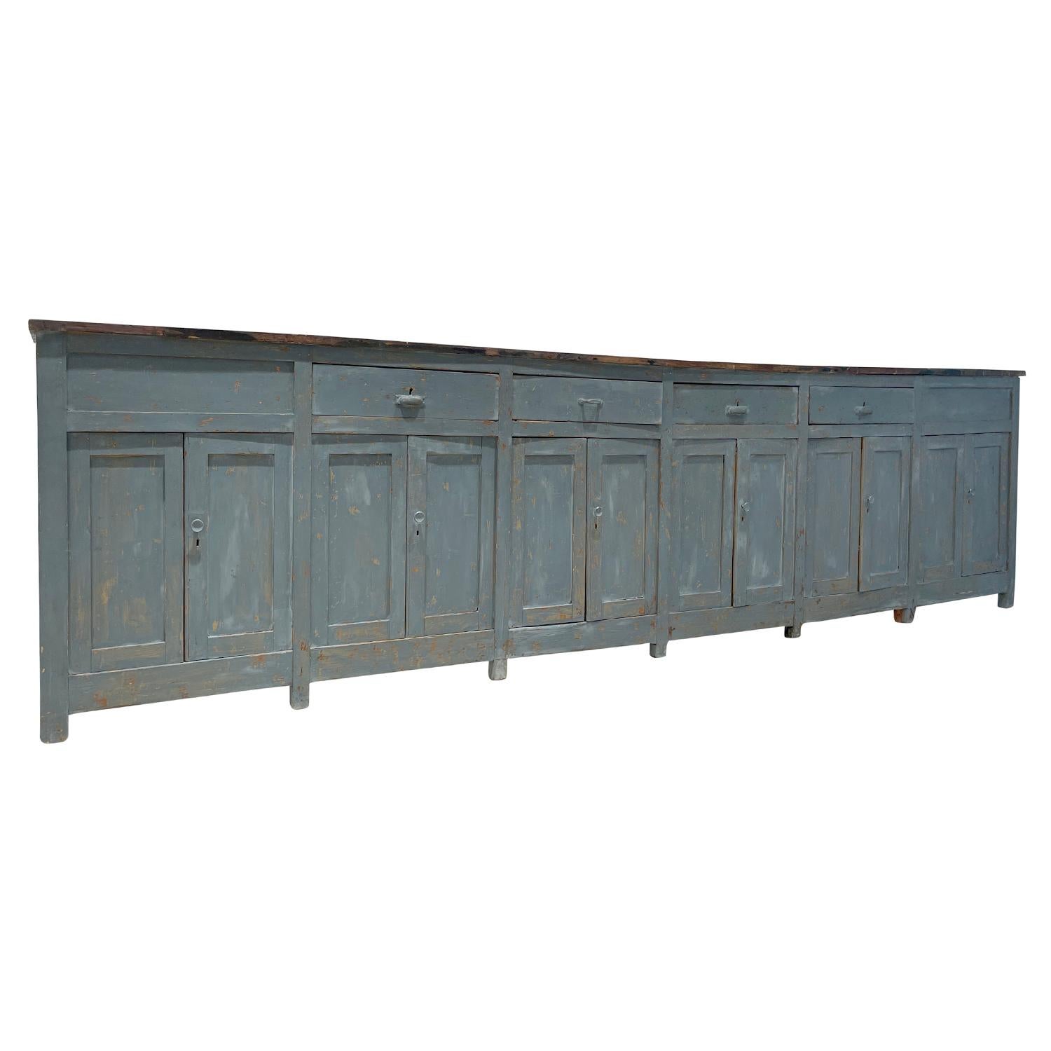 A large, antique Provencal credenza or sideboard in grey blue patina with four drawers and six pairs of doors, in good condition. The top has been painted in irregular hues of bronze tones. Painted Pinewood, minor repairs. Wear consistent with age