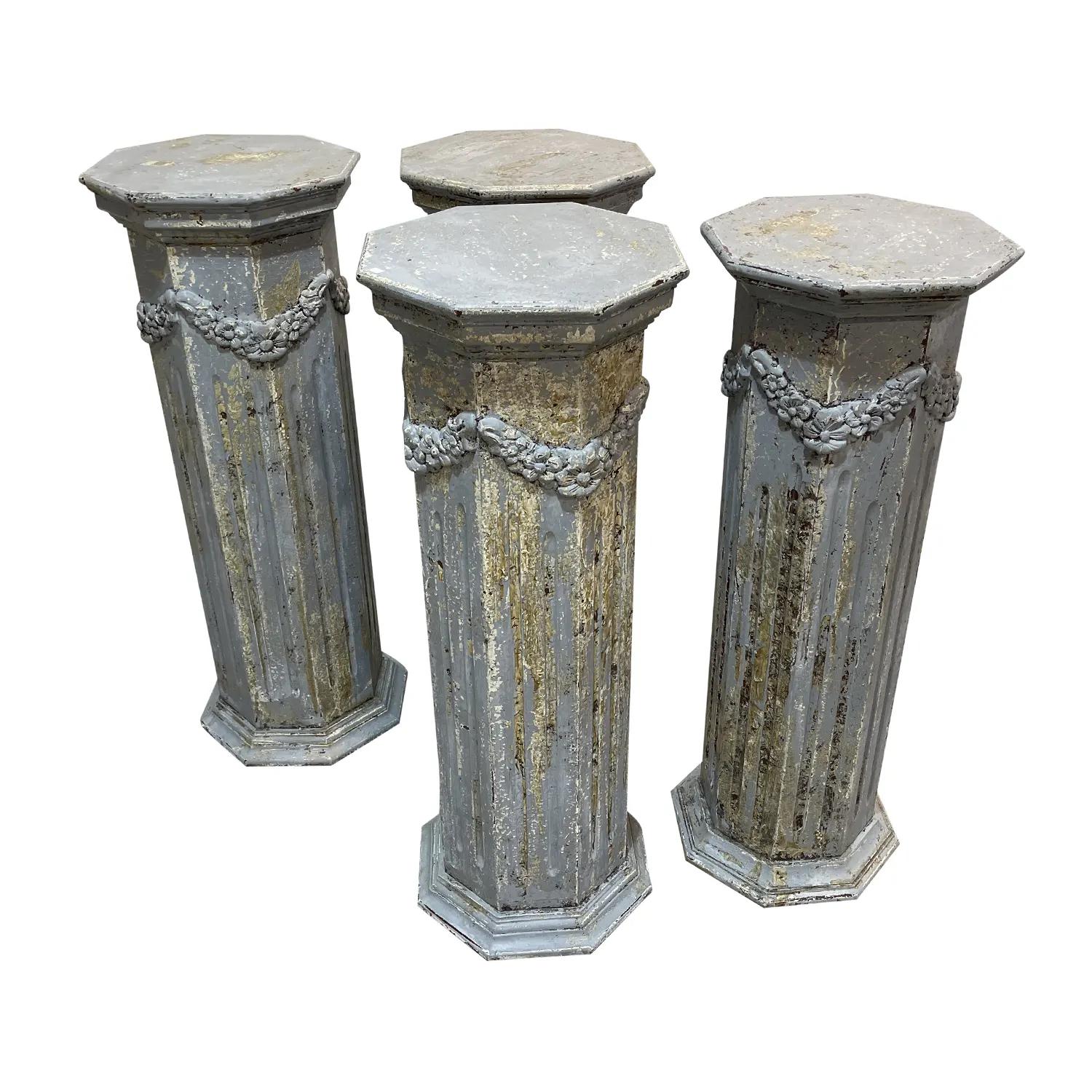 An antique set of four 19th century pedestals of octagonal shape on the top and bottom, in good condition. The French pedestals are made of hand crafted painted Pinewood, abundantly decorated with garland swags and mounted on a fluted body. These