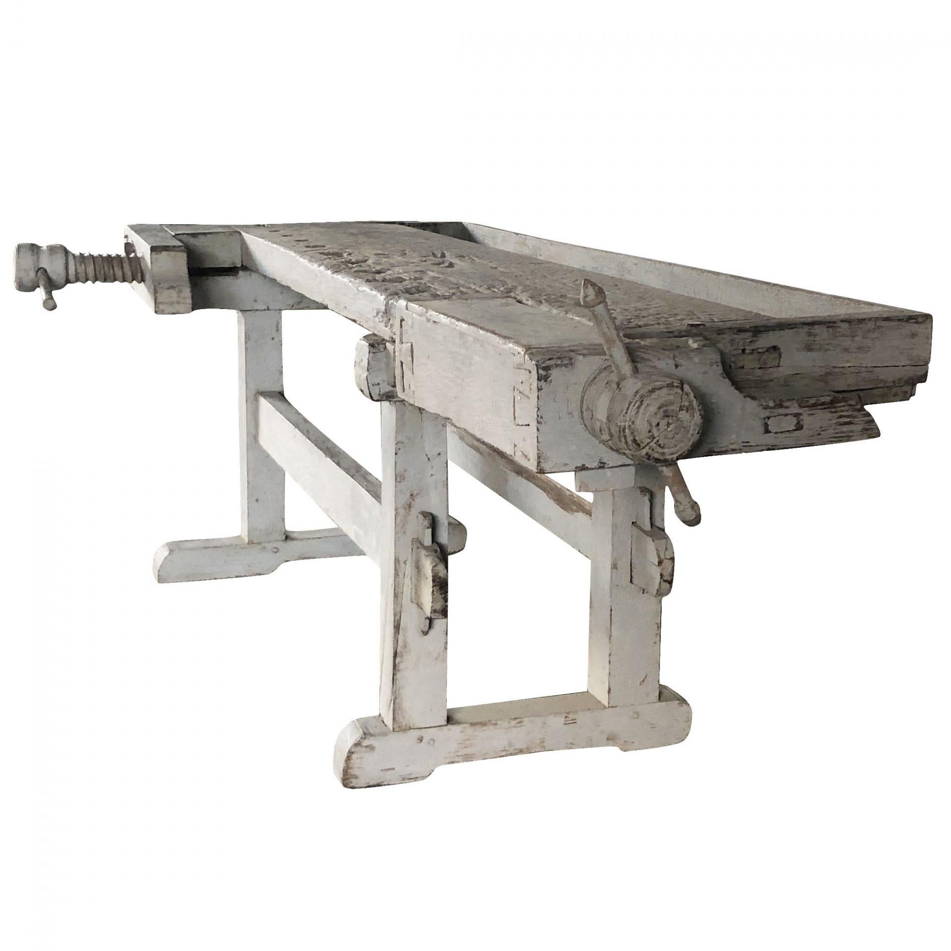 A 19th Century, Swedish Gustavian working bench made of hand crafted painted Pinewood in a pale grey antique finish, in good condition. The detailed Scandinavian carpenter bench is composed with its original wooden screw, standing on four wooden