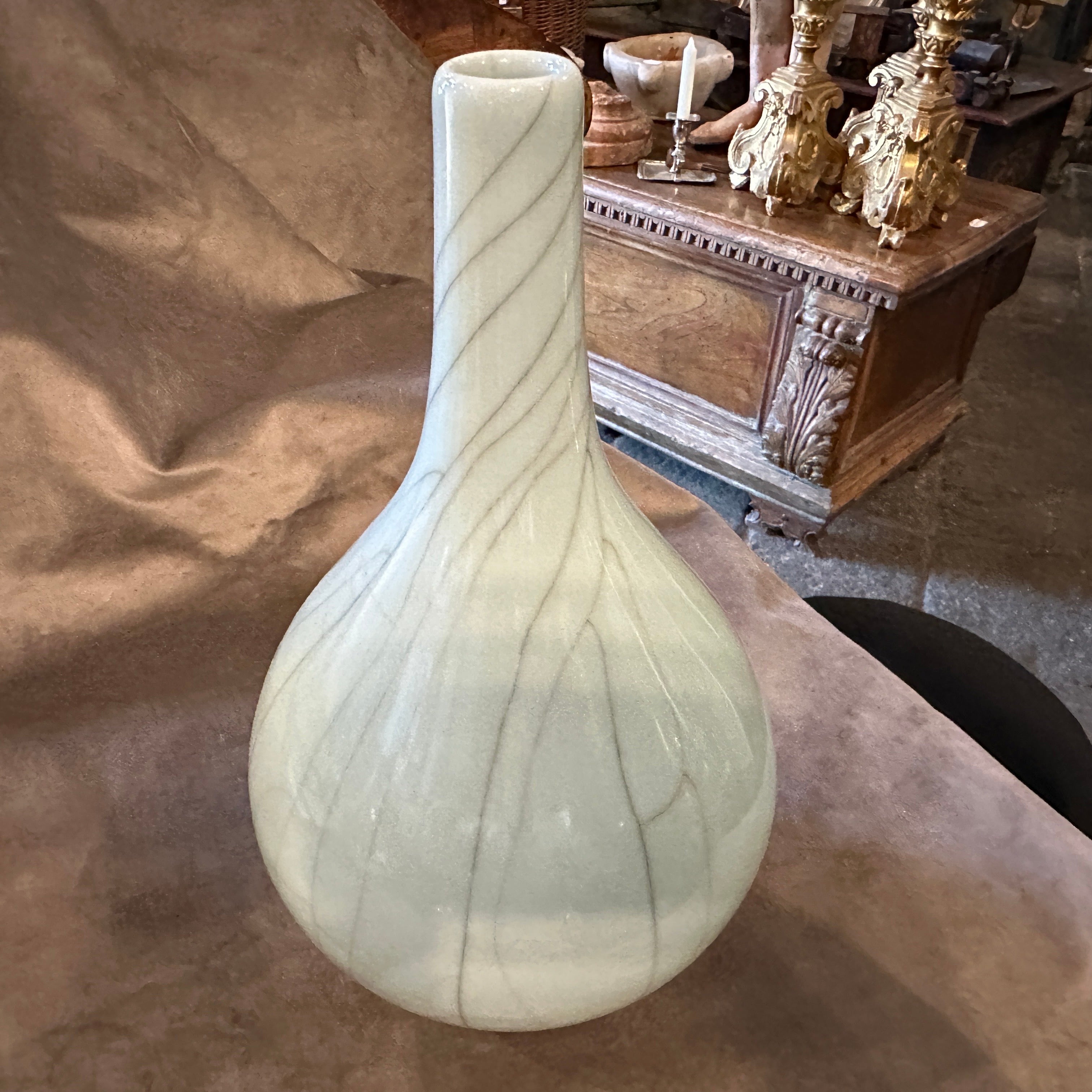 A simple and elegant round Celadon vase manufactured in China in the late 19th century, the vase is covered overall with a crackled grey celadon glaze. The glaze it's smooth and even, with a slight sheen that catches the light. Celadon is a type of