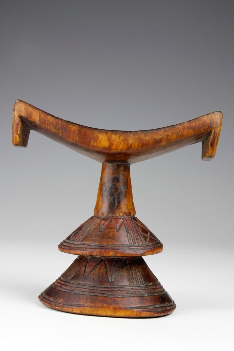 Datant de la fin du XIXe siècle, il s'agit d'une forme fine et plus rare d'appui-tête éthiopien avec une base conique à deux niveaux. 

La base est ornée de motifs profondément gravés de croix et de stries circulaires, et deux ergots orientés vers