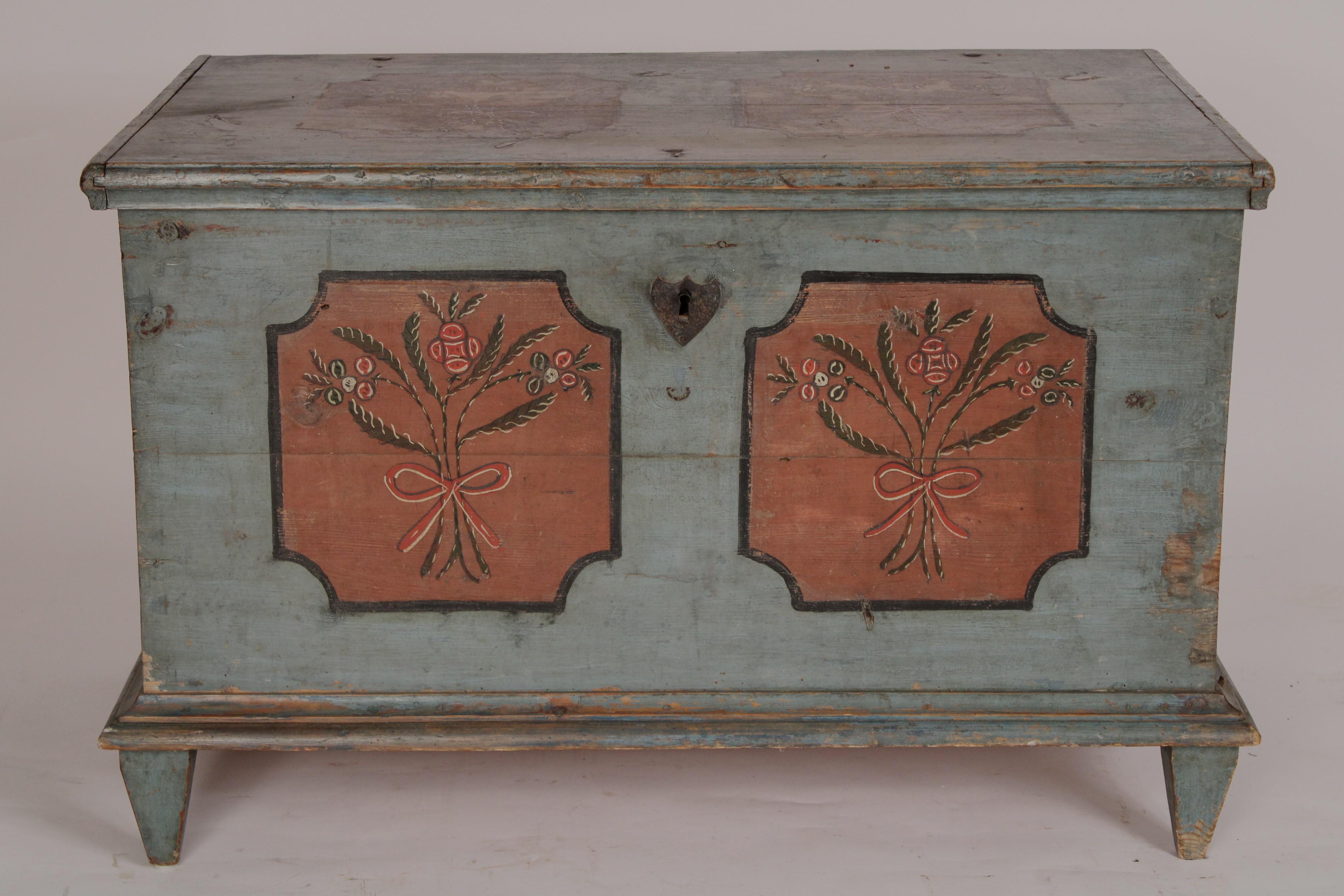 Gustavian painted pine trunk, 19th century. With a rectangular overhanging top with two cartouches inset with floral decoration, the front with painted floral panels and a shield shaped escutcheon, sides with painted floral panels, resting on square