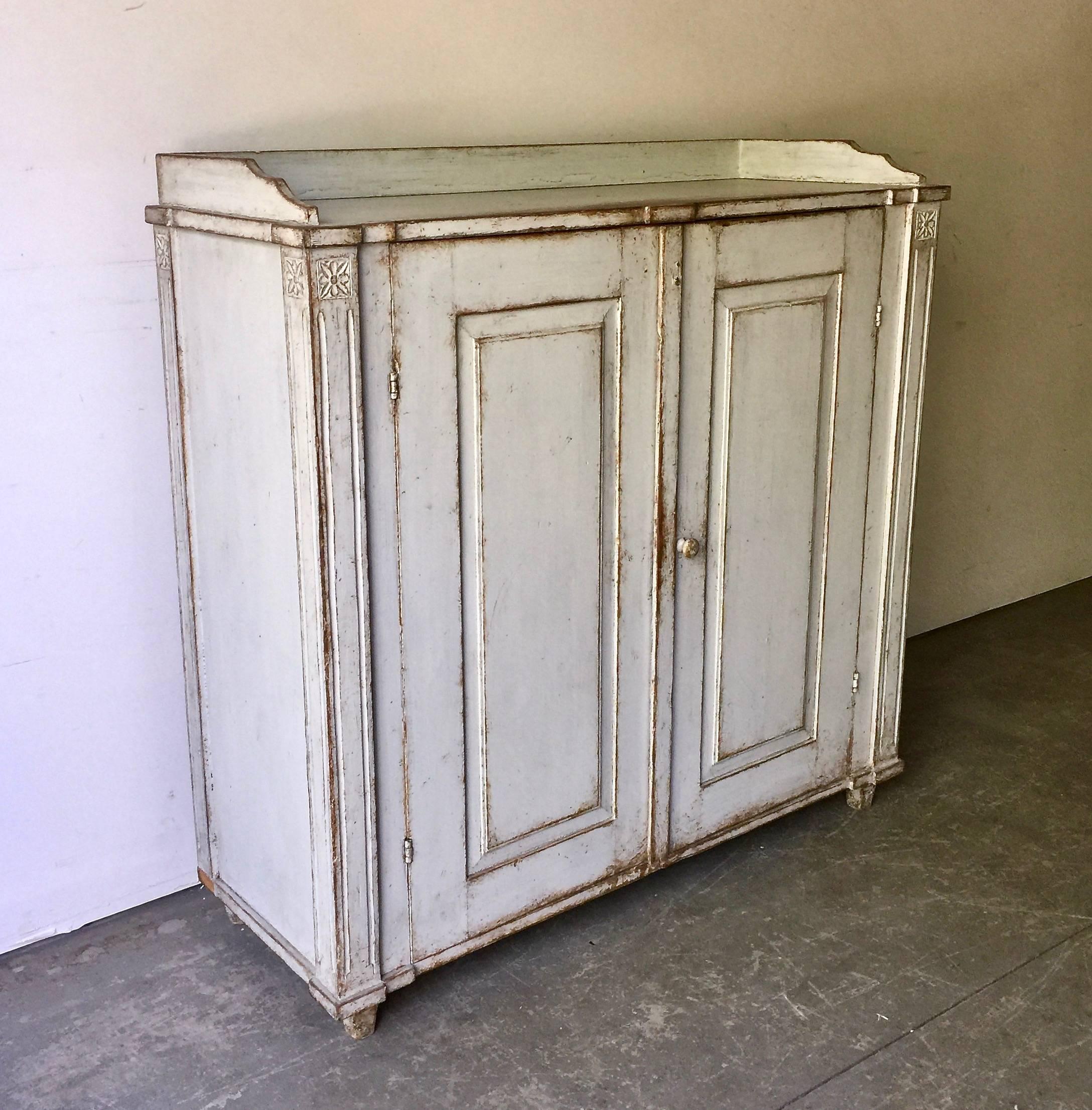 Period Gustavian sideboard, circa 1810, Sweden with wonderful worn pale blue and grey patina. Classic proportions with carved panel doors, carved side posts with charming rosettes, gallery wooden top and tapered feet. Original hardwares.
More than