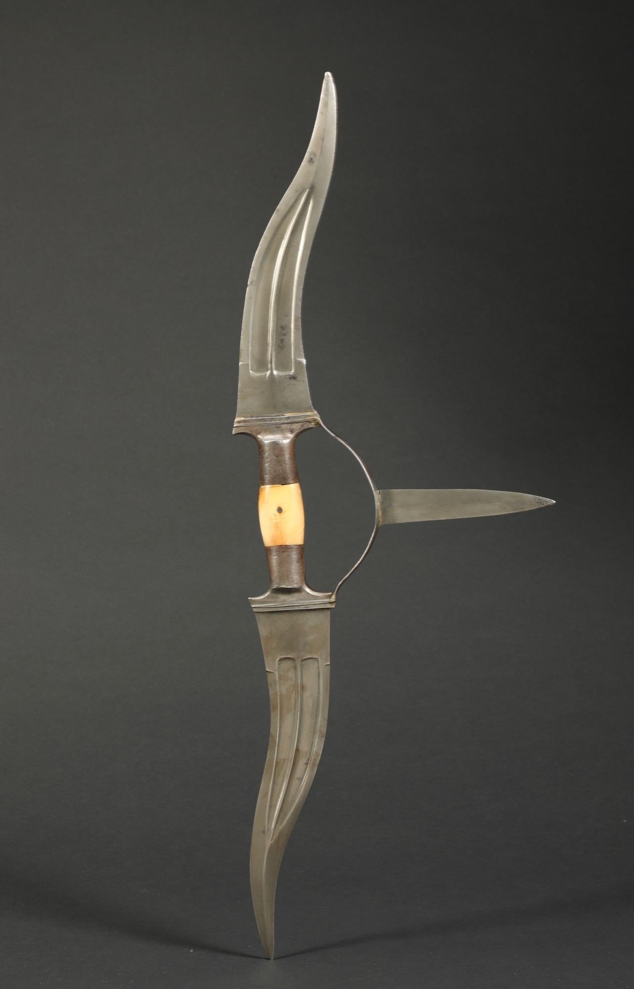 The Haladie dagger is one of the more unusual weapons from India. The two large blades are wellformed with a high center ridge and two fullers. The hand guard has a small double edged blade. The handle has plaques of bone that show a good patina