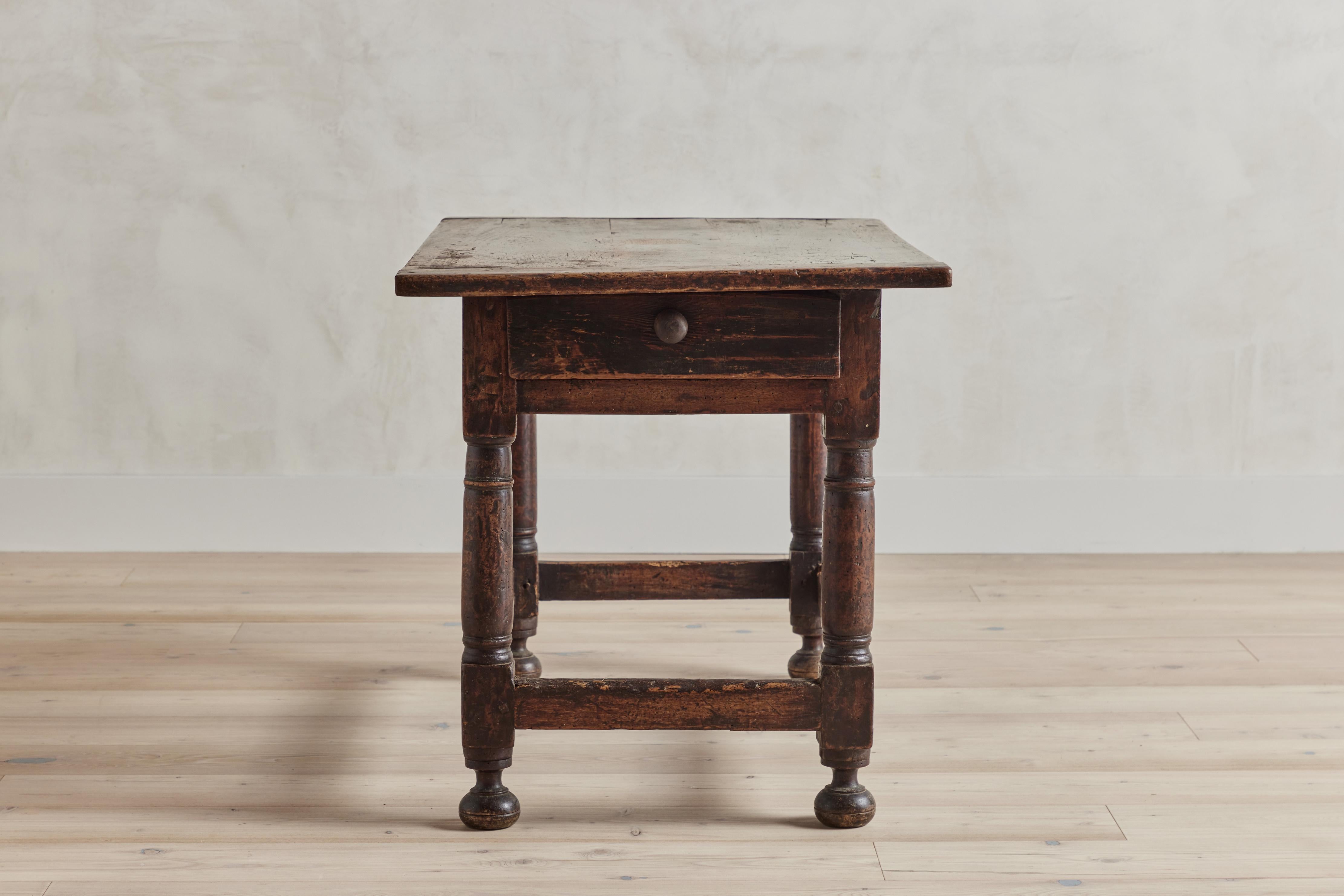 19th century hall table from France with turned wood legs on bun feet. This table features a single drawer. Wood shows visible wear from age and use.