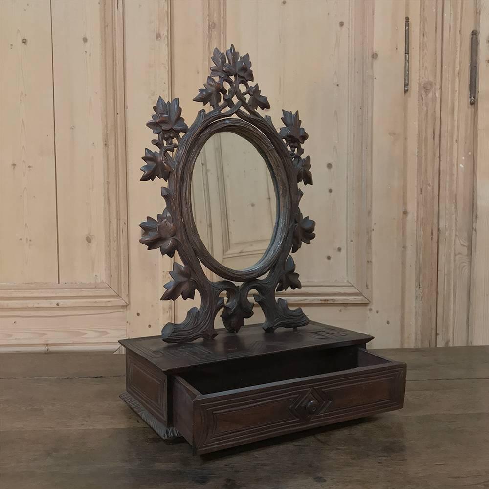 19th century hand-carved black forest vanity mirror-box was sculpted from solid fruitwood in the naturalistic form that is definitive of the region, appearing to be the flora that exists in the beautiful Alpine surroundings of the area. The oval