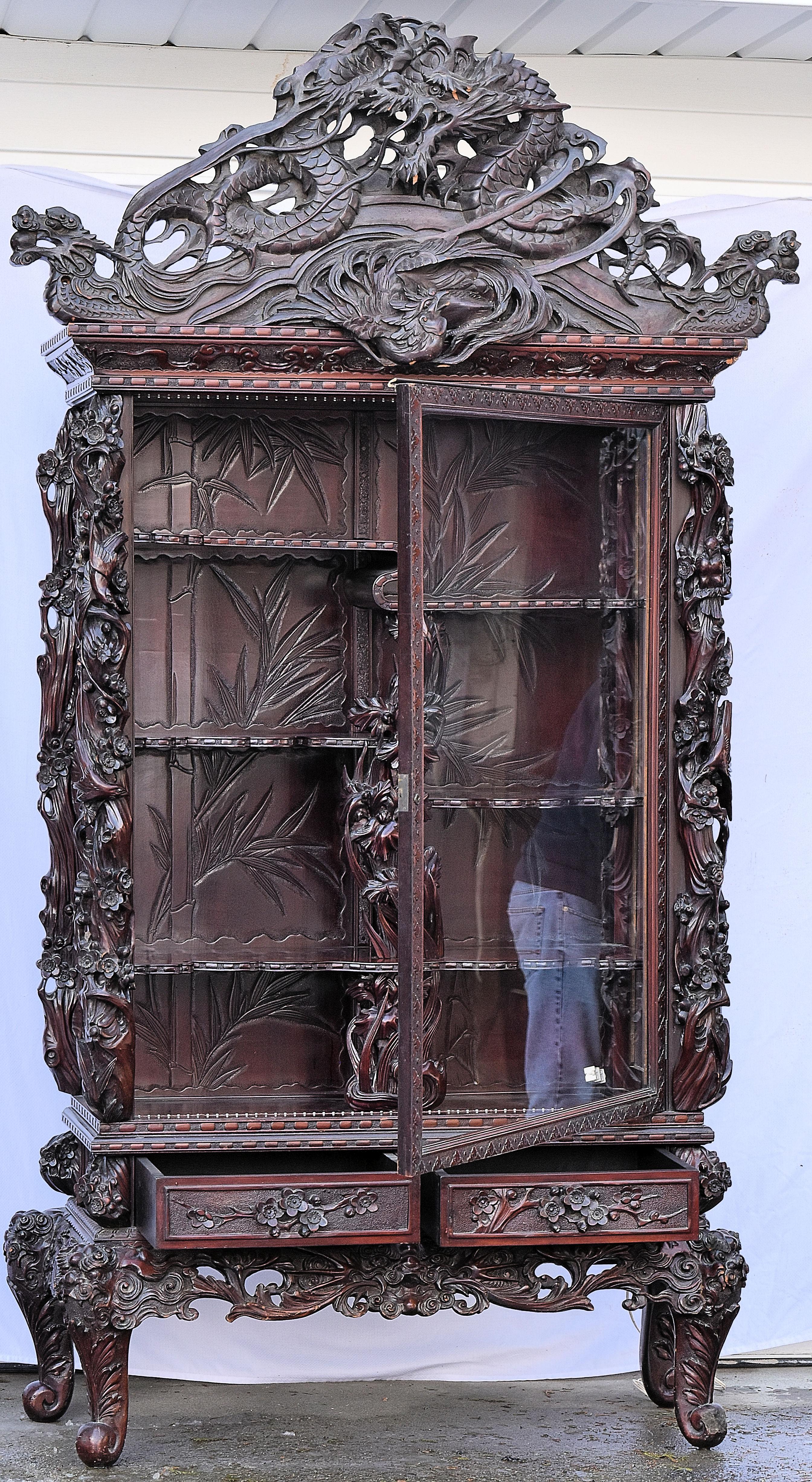 Heavily carved Japnese display cabinet featuring multiple dragons, top to bottom. The cabinet features a single, large glass door with 6 shelves inside and two drawers underneath.

The cabinet and base come apart for easy moving.

Showcase
Overall