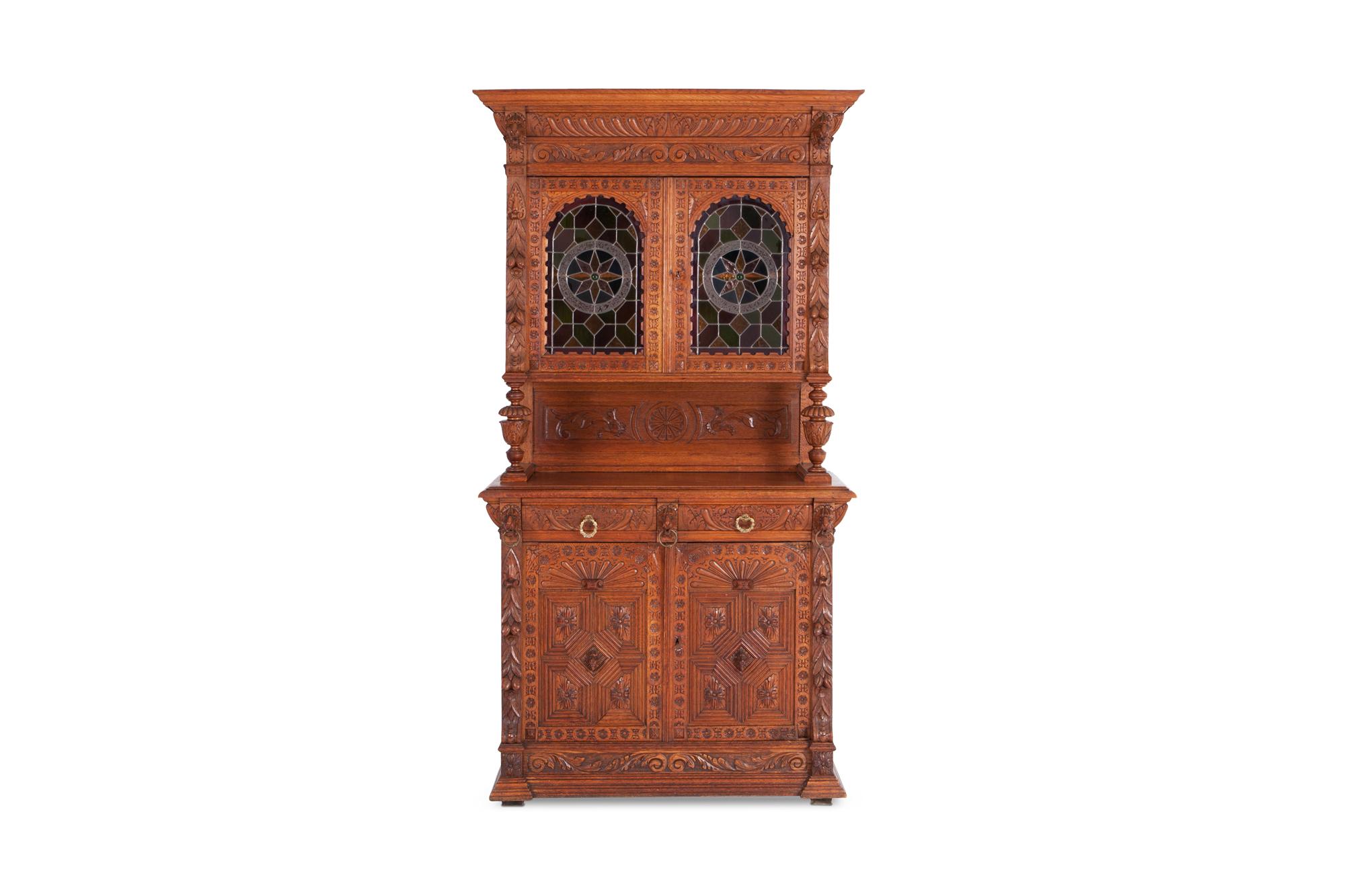 Henri II style bibliotheque, or bookcase, made of solid oak with extraordinary fine carved details and columns. 

Drawers with original brass pulls. The top has glass paned doors with colored glass. 

Hand-carved in Mechelen for an Antwerp