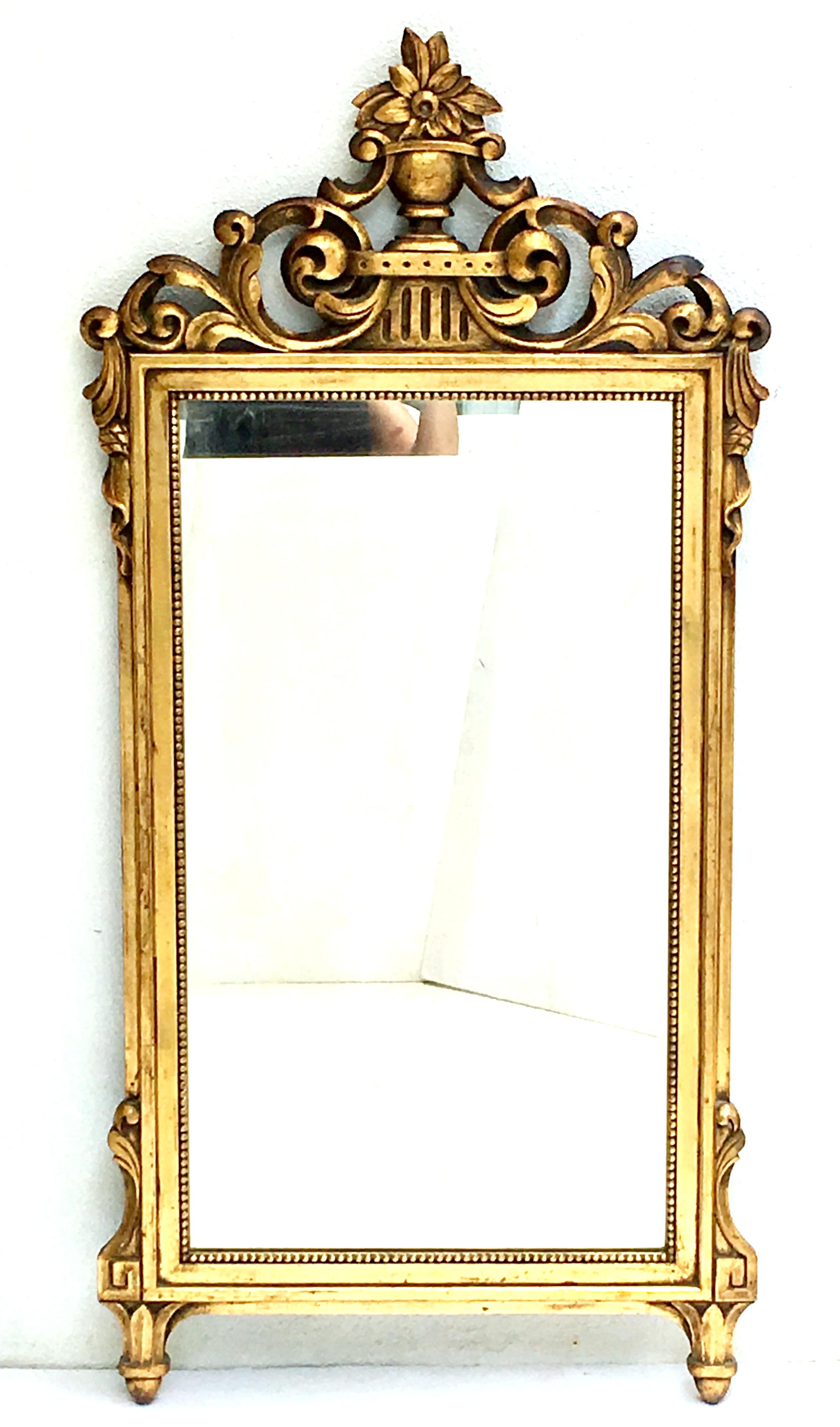 19th Century hand carved walnut gold gilt wood full length mirror in the French Regency style. This substantial, finely crafted hand carved gold gilt frame mirror features a Classic French Regency motif of a central top urn, floral and scroll motif