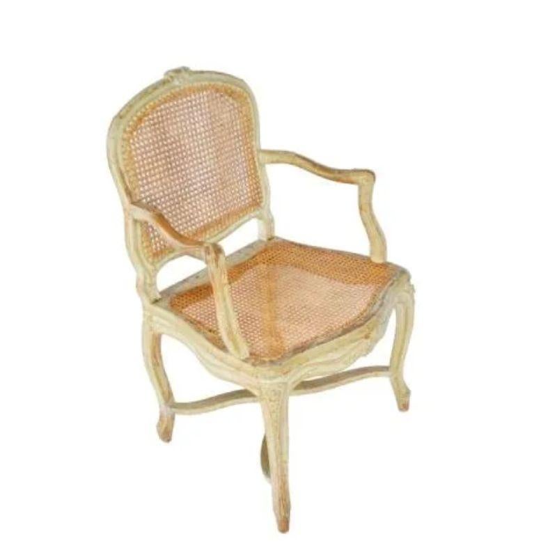 A 19th Century Louis XV style hand carved, caned arm chair with hand painted details.  The French style fauteuil has a curved back and curved front to the seat with hand carved floral details on the seat back and seat apron.  The cane on the seat