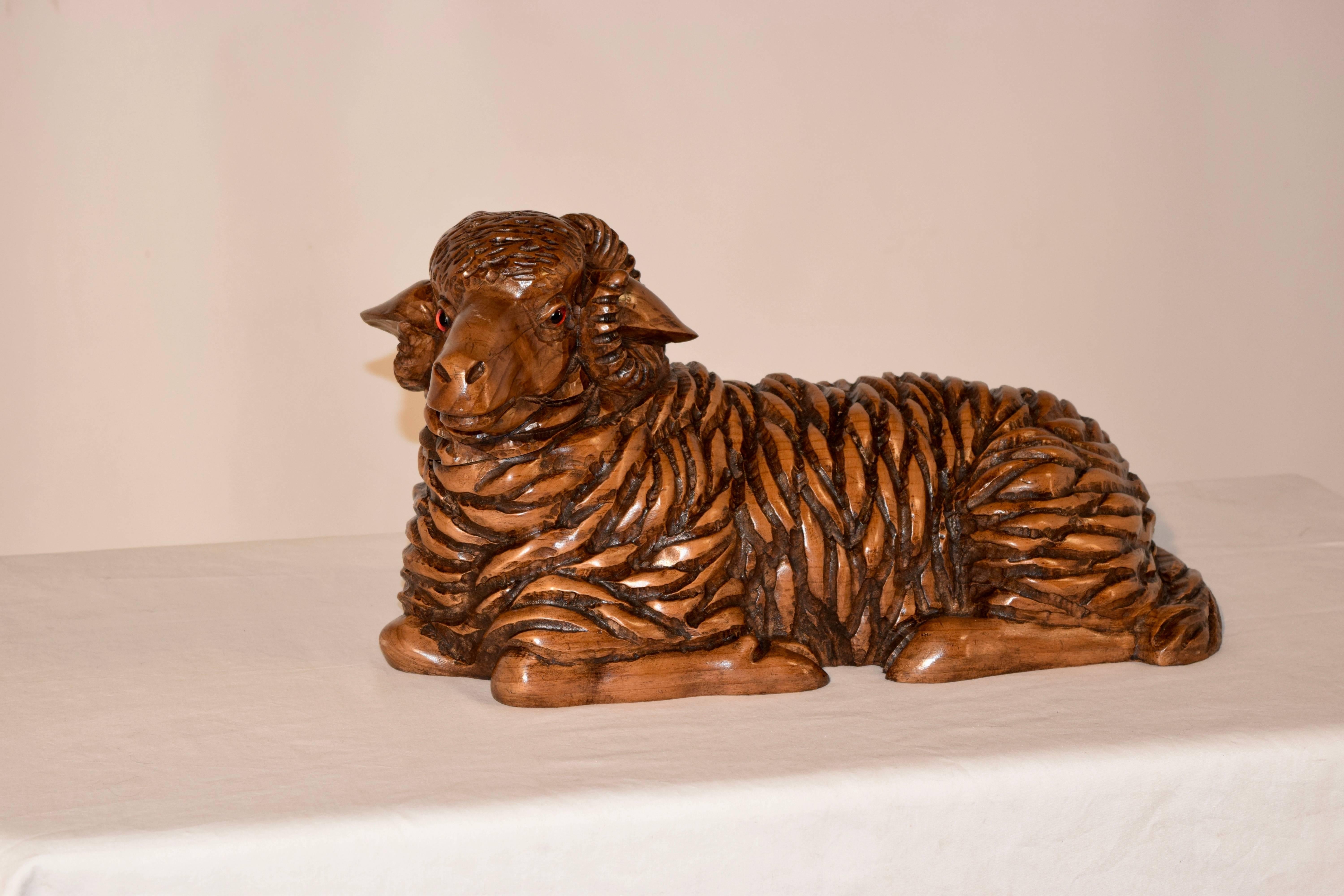 19th century fruitwood figure of a sheep which has been meticulously hand carved. Glass eyes. The sheep is in a resting pose.