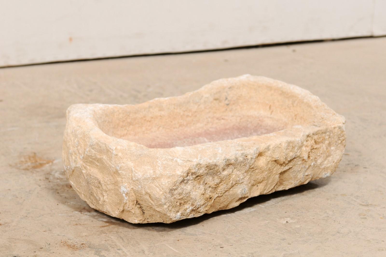 Spanish carved stone trough from the 19th century. This antique trough from Spain, with its oblong shape, has been hand carved out of a single piece of stone, having a nicely textured surface. In addition to standing alone as a decorative object, it