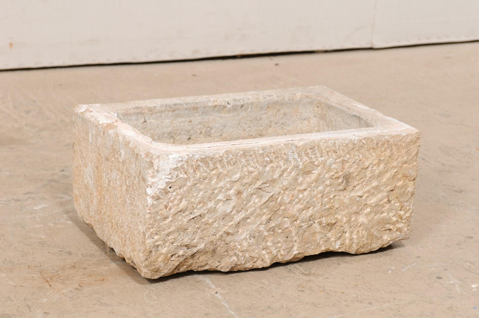 A Spanish carved stone trough from the 19th century. This antique trough from Spain, with it's rectangular shape, has been hand carved out of a single piece of stone, having a nicely textured surface. In addition to standing alone as a decorative