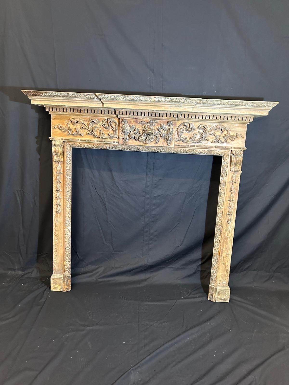 A 19th Century intricately carved wooden fireplace. Featuring columned scrolled legs, central tablet with centralised pomegranate and foliage details either side.